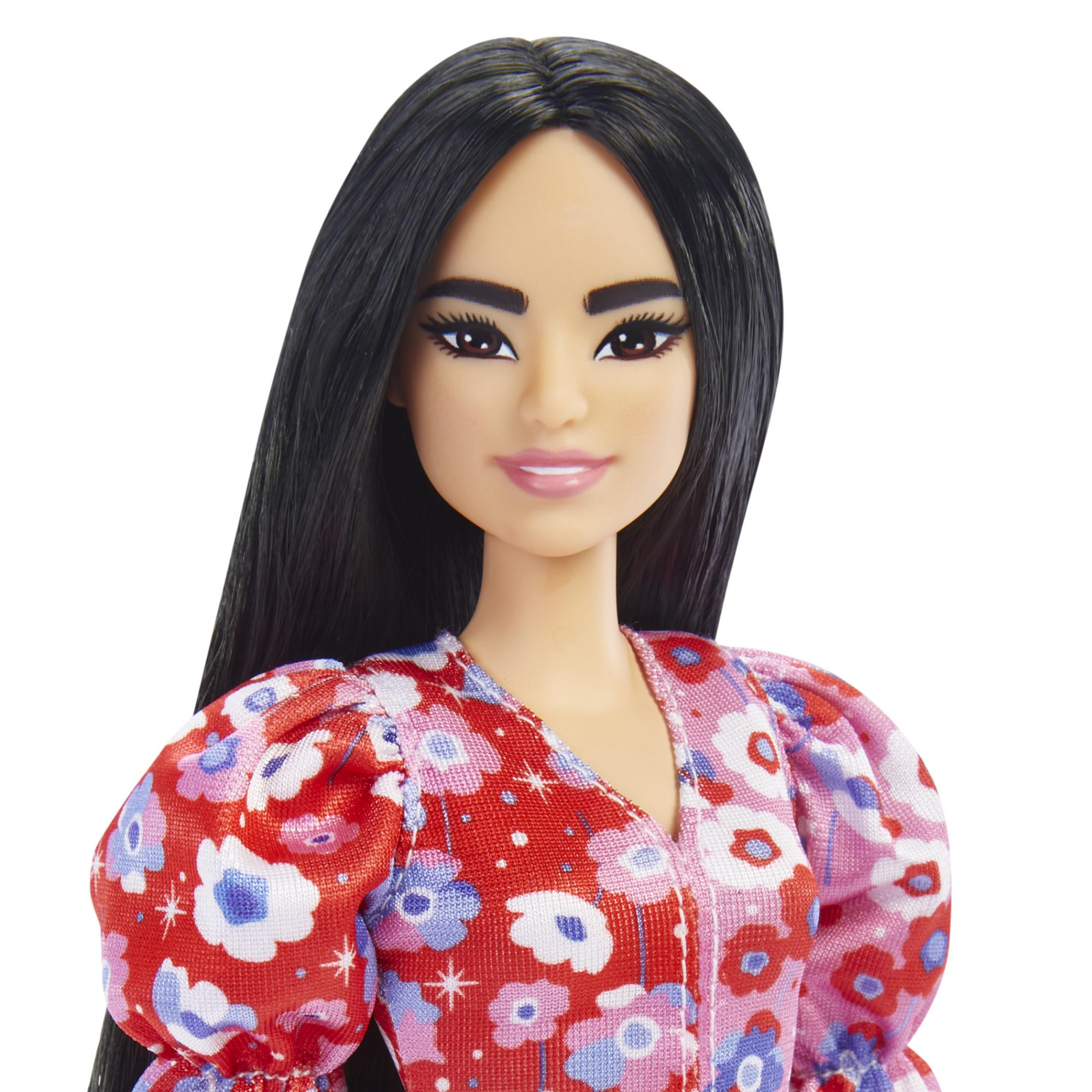 Eine Barbie-Puppe mit langen schwarzen Haaren, die ein Blumenkleid trägt, mit neutralem Hintergrund.