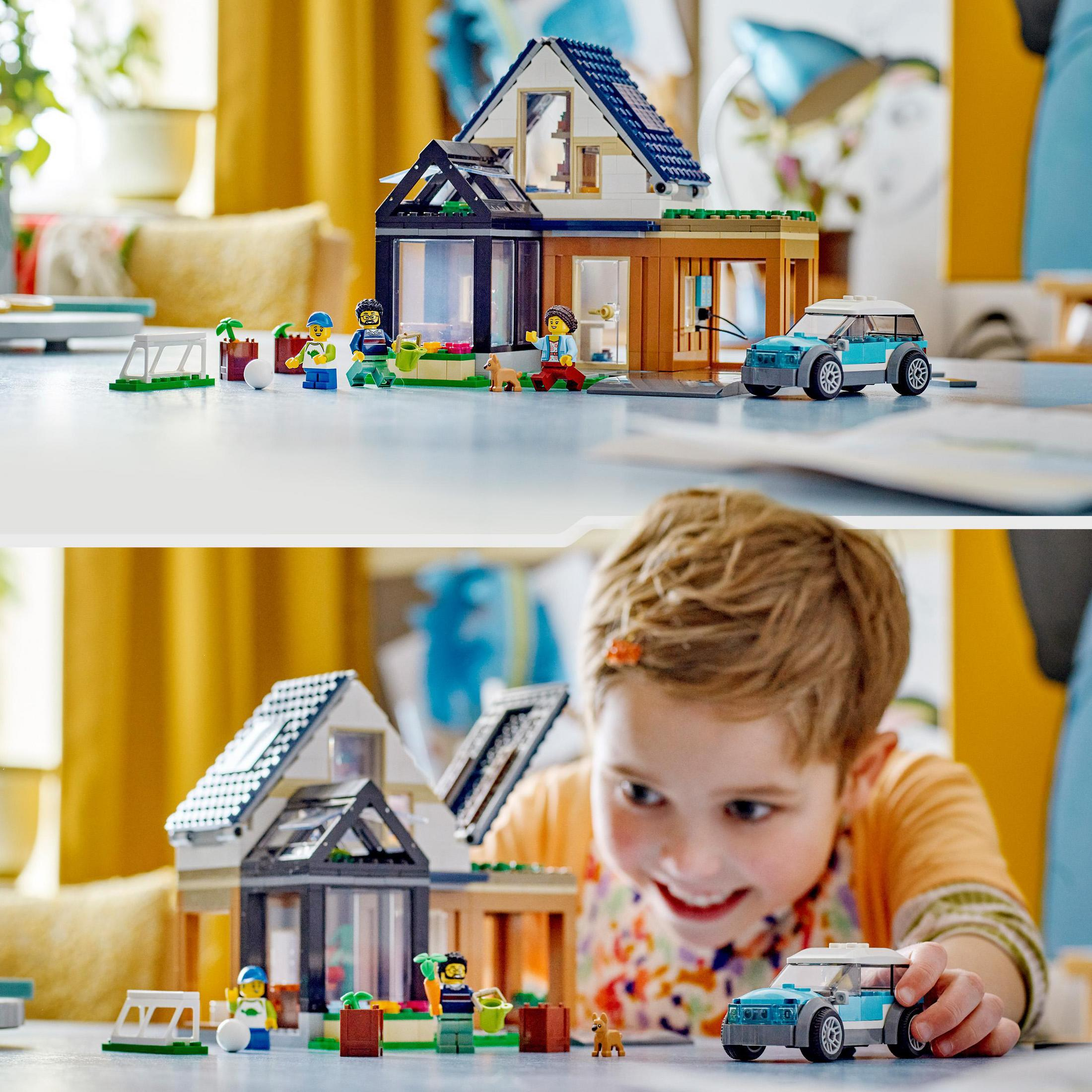Ein Lego-Hausmodell mit Figuren und einem Auto. Ein Kind spielt mit dem Modell und lächelt.