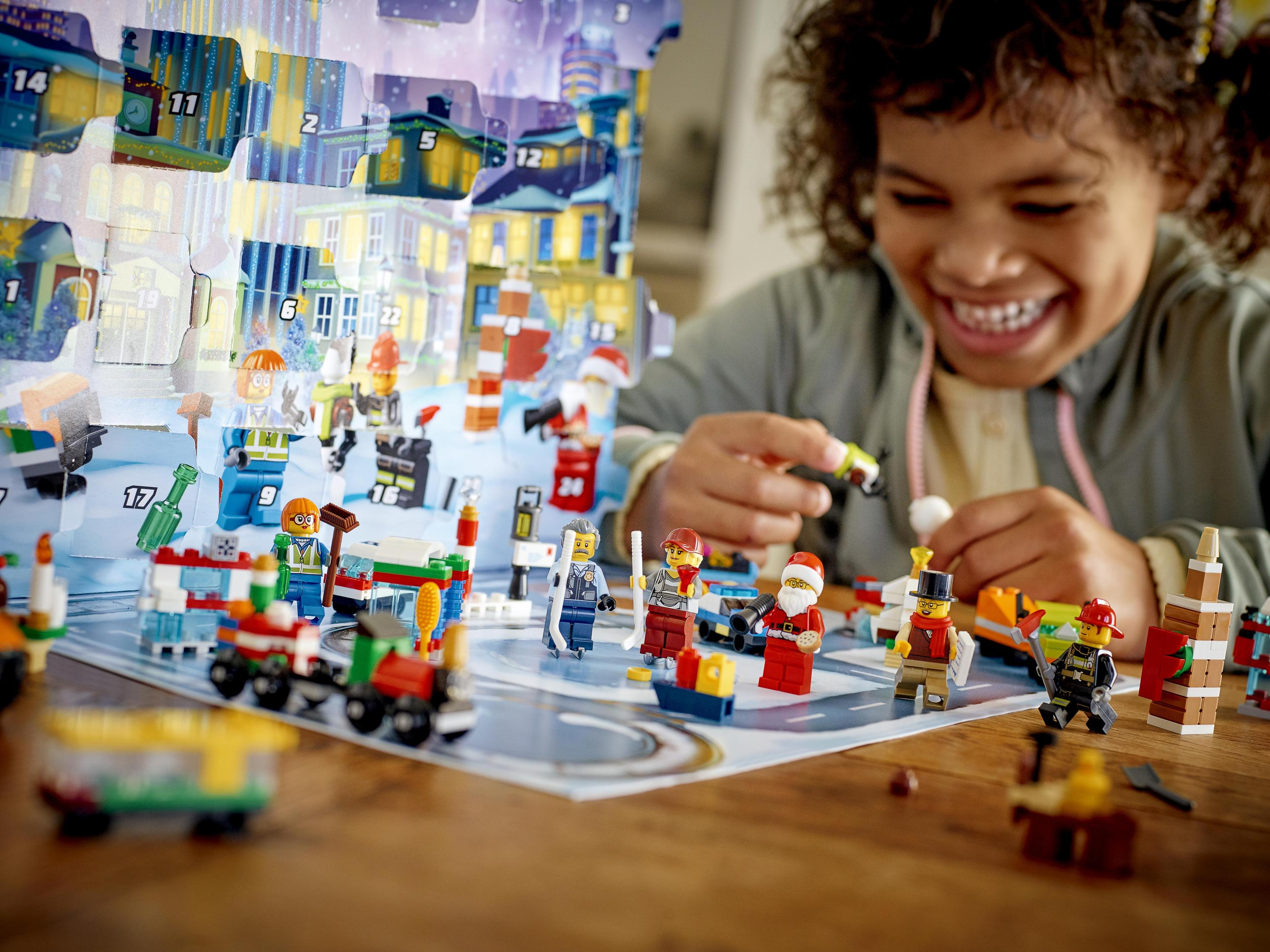 Mädchen mit Lächeln öffnet Adventskalender. Kalender hat nummerierte Türen und Lego-Figuren.