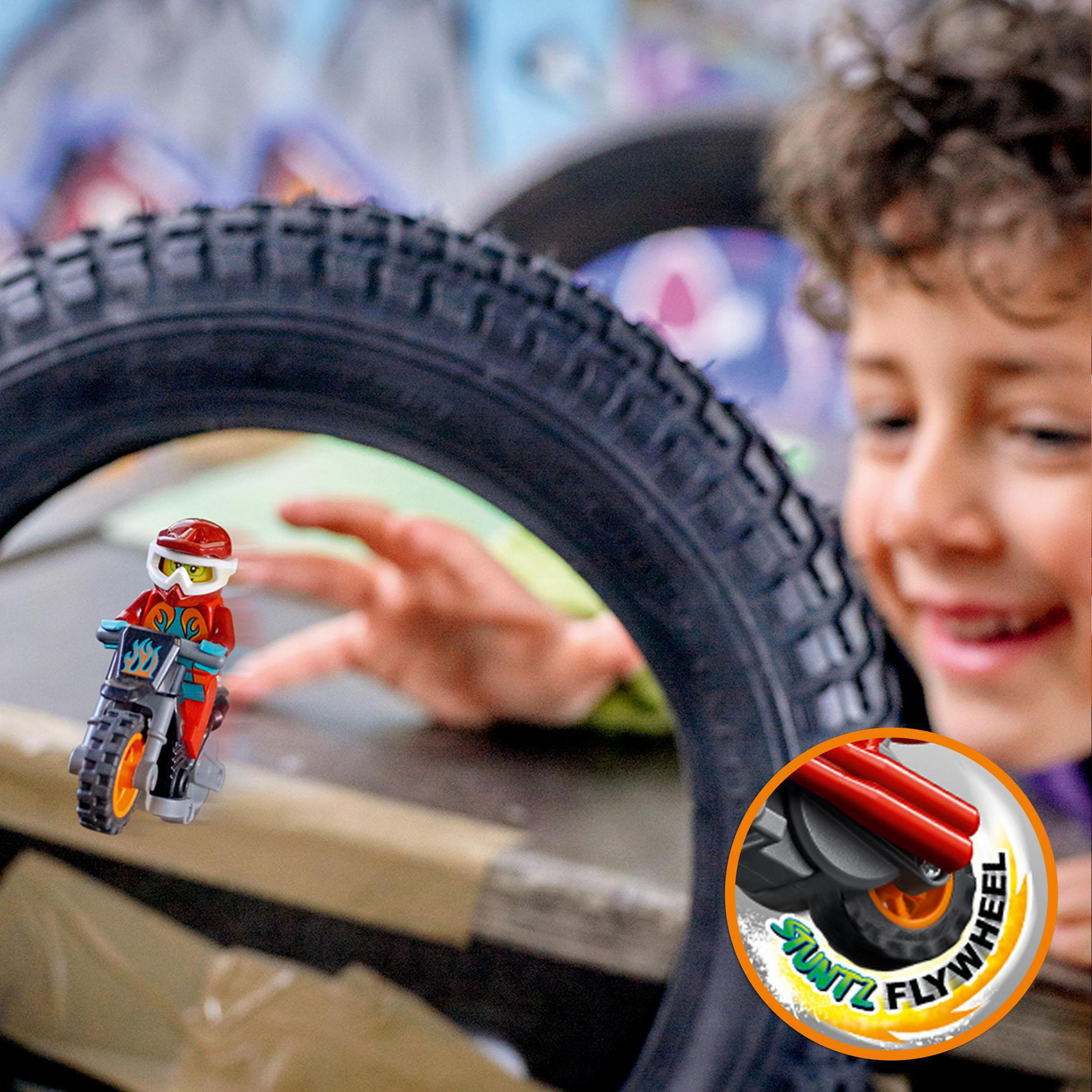 Ein Kind lächelt über ein LEGO Motorradspielzeug, das in einem Reifen zusammengebaut wird.
