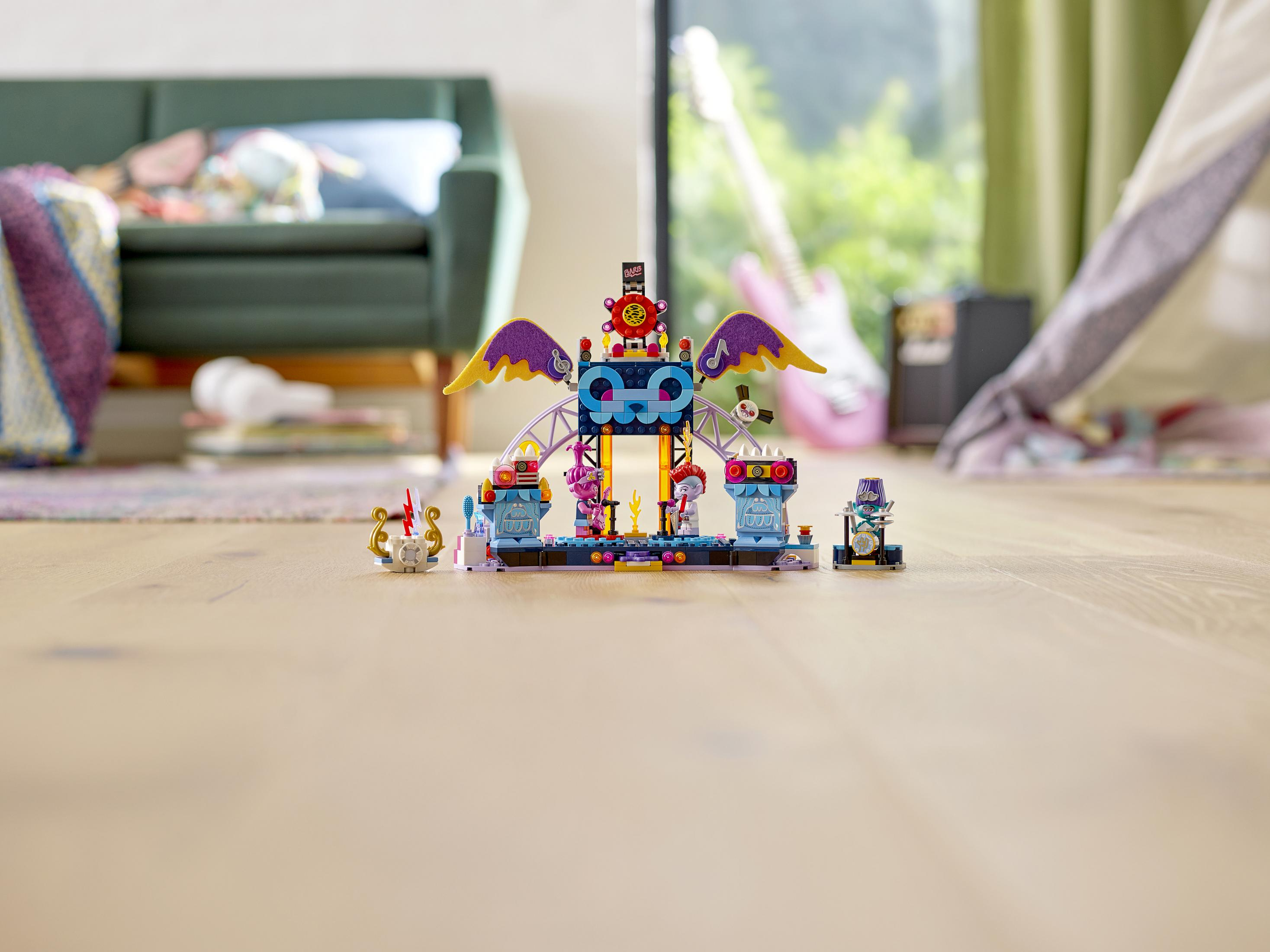 LEGO Bühnenbild mit Figuren, einer rosa Gitarre und einem grünen Sofa auf Holzboden.
