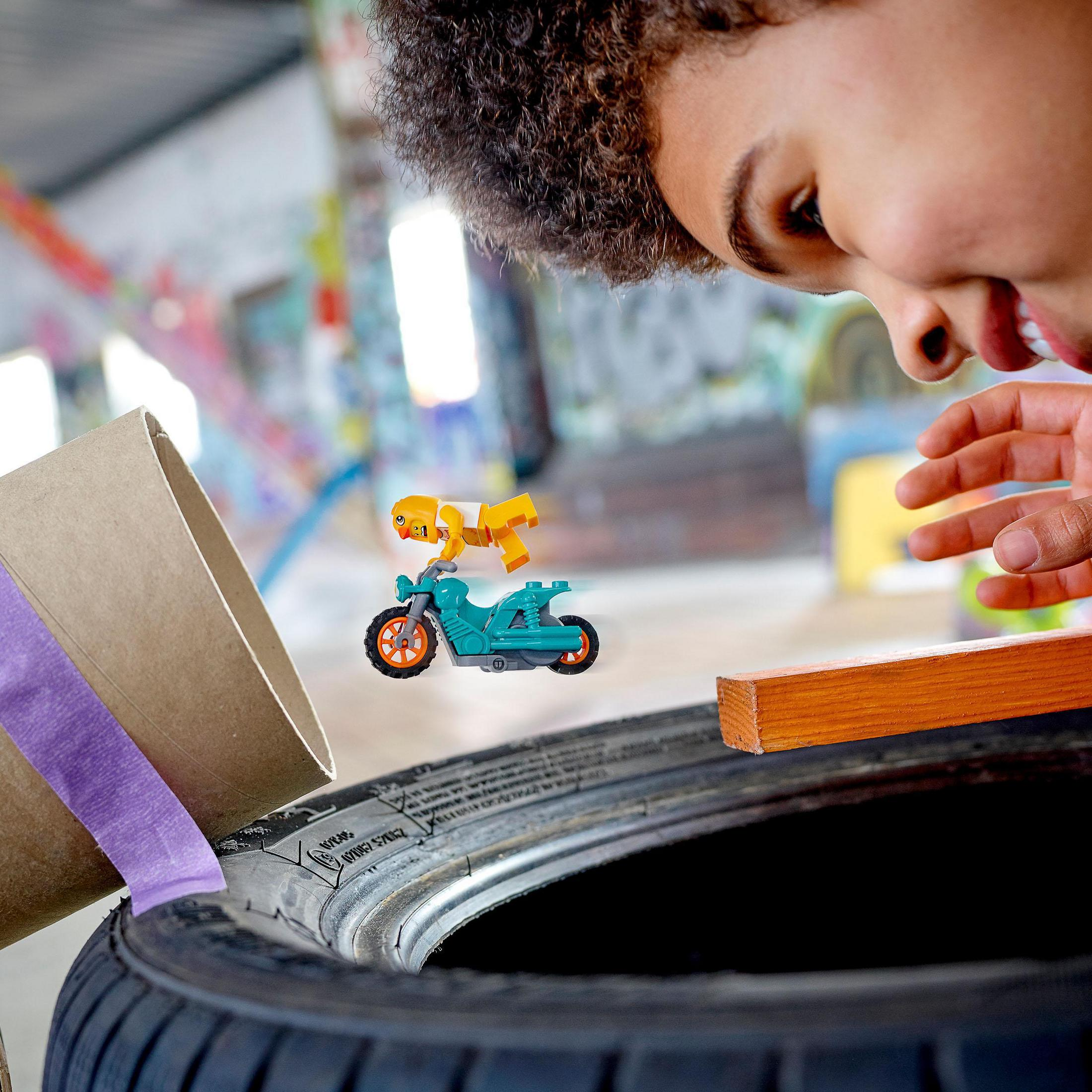 Person betrachtet Spielzeugmotorrad mit Lego-Figur in Graffiti-Raum.