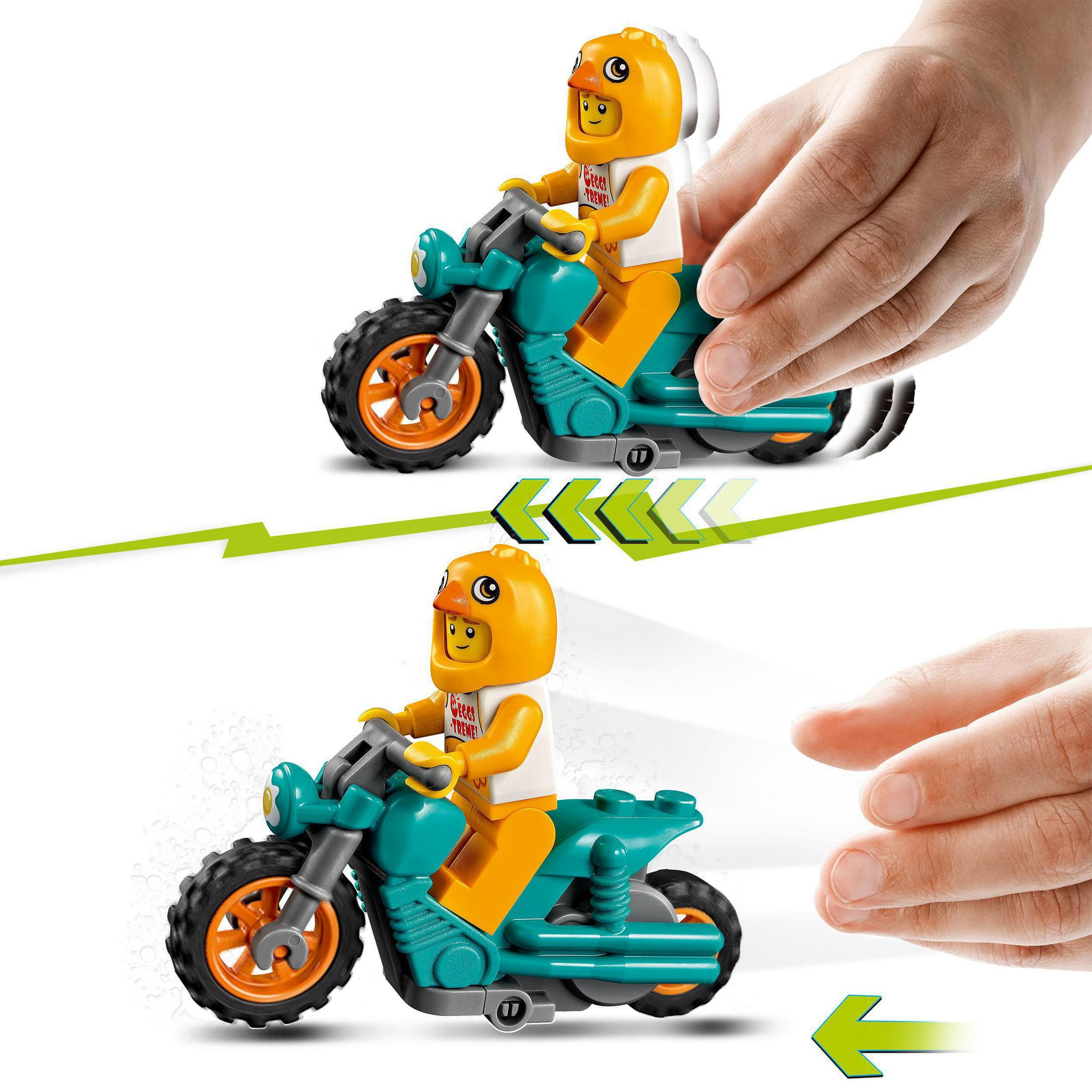 Spielzeugmotorrad mit einer Figur in Form eines Kükenhelms. Hände werden gezeigt, die das Spielzeug bewegen.