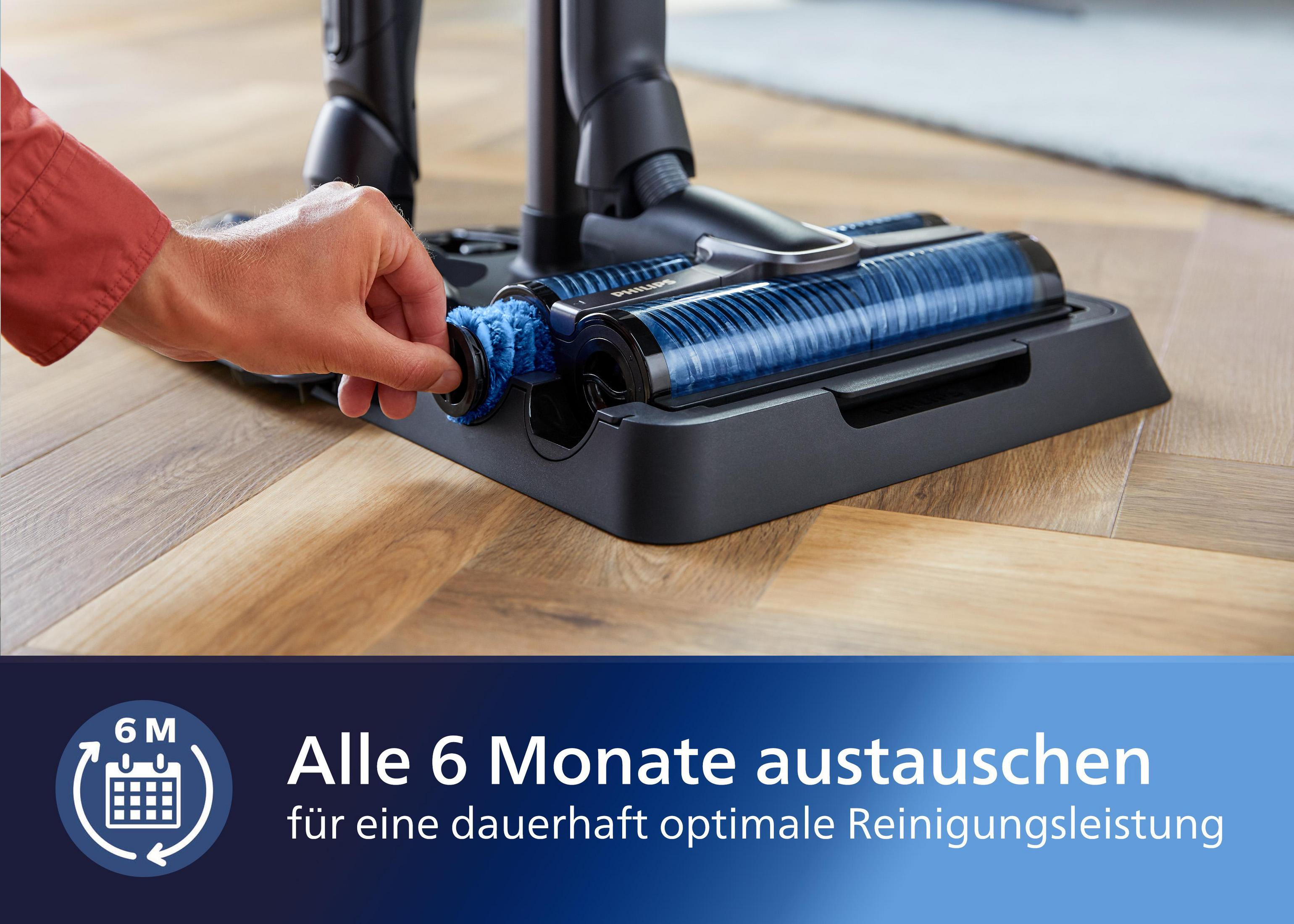 Hand entfernt eine Bürste vom Staubsaugerkopf. Blaues und schwarzes Gerät, Holzboden.