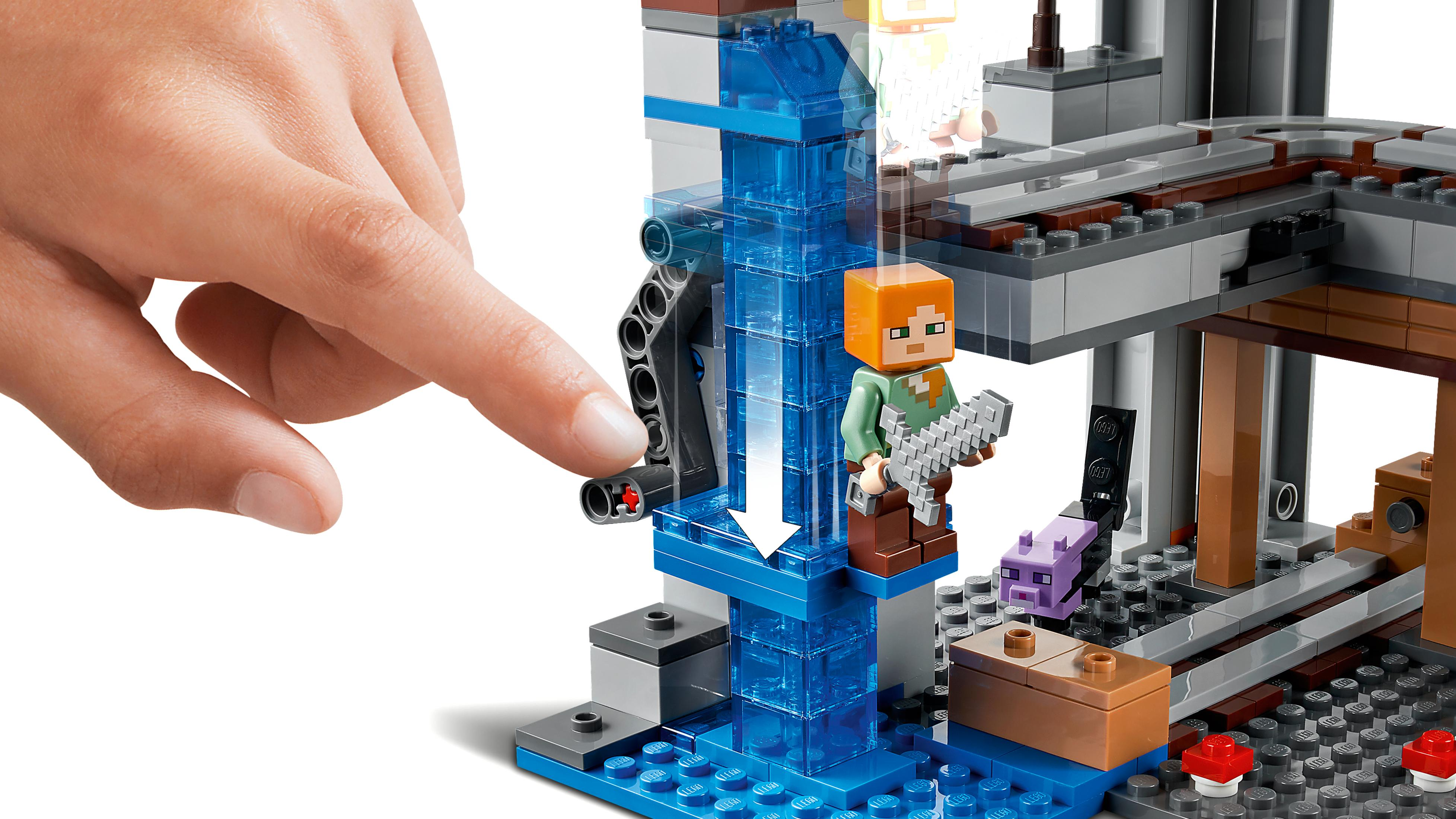 Hand bedient ein Lego Minecraft Set. Eine Figur steht vor einem Wasserfall. Blöcke und ein lila Mob.