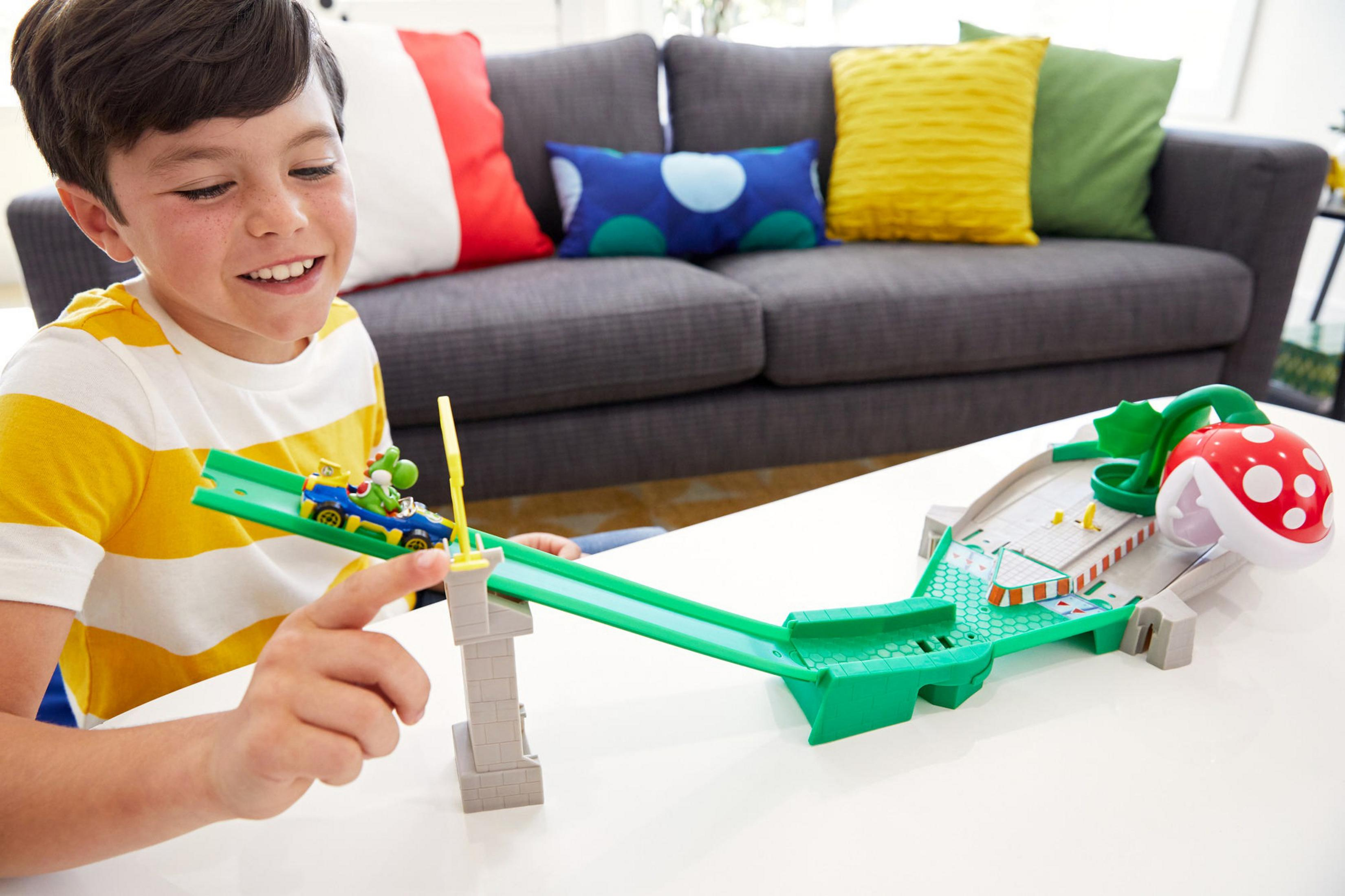 Chłopiec bawiący się torem zabawkowym Mario Kart. Tor jest zielony z rośliną piranha.