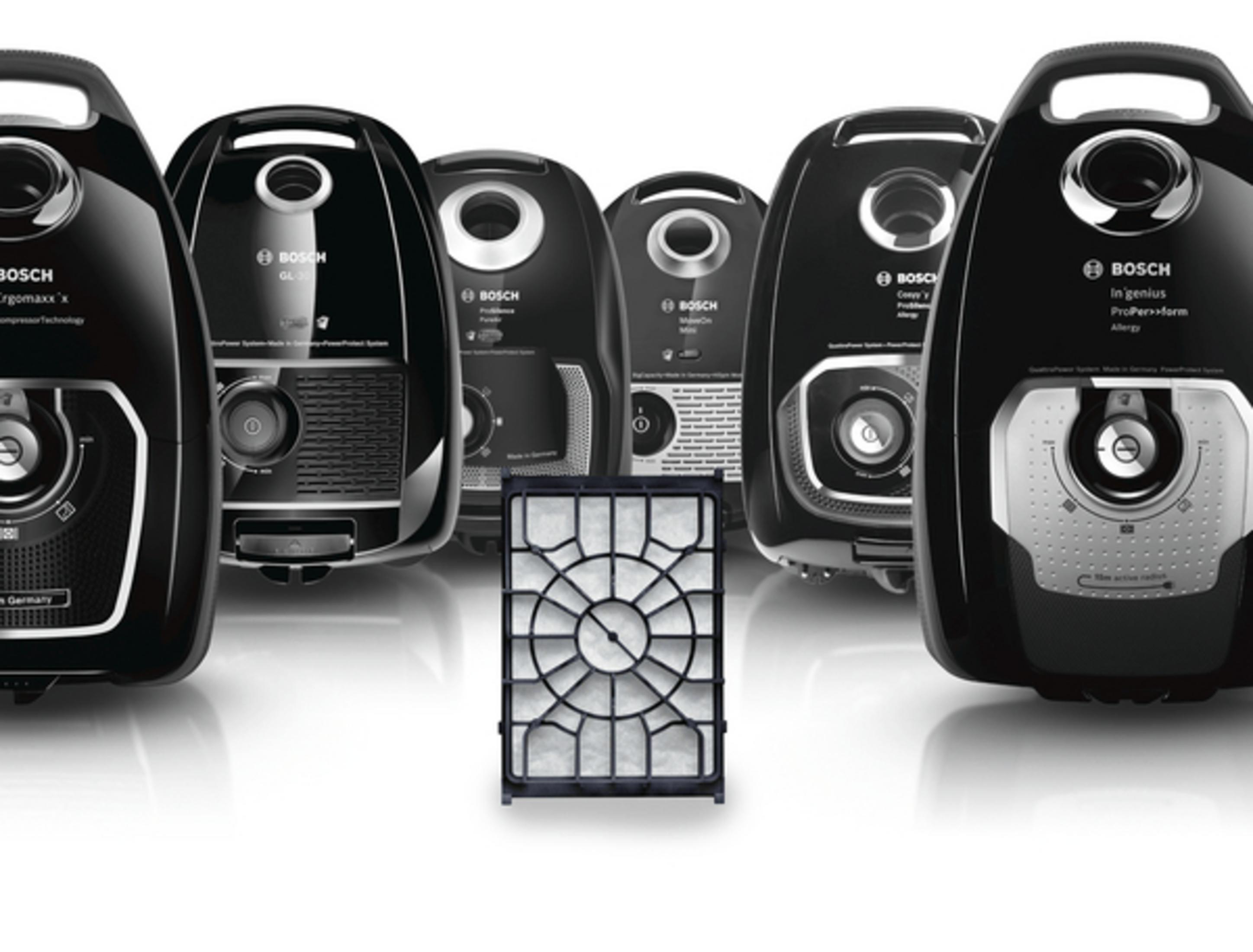 Wiele czarnych odkurzaczy i filtr z przodu. Białe tło.