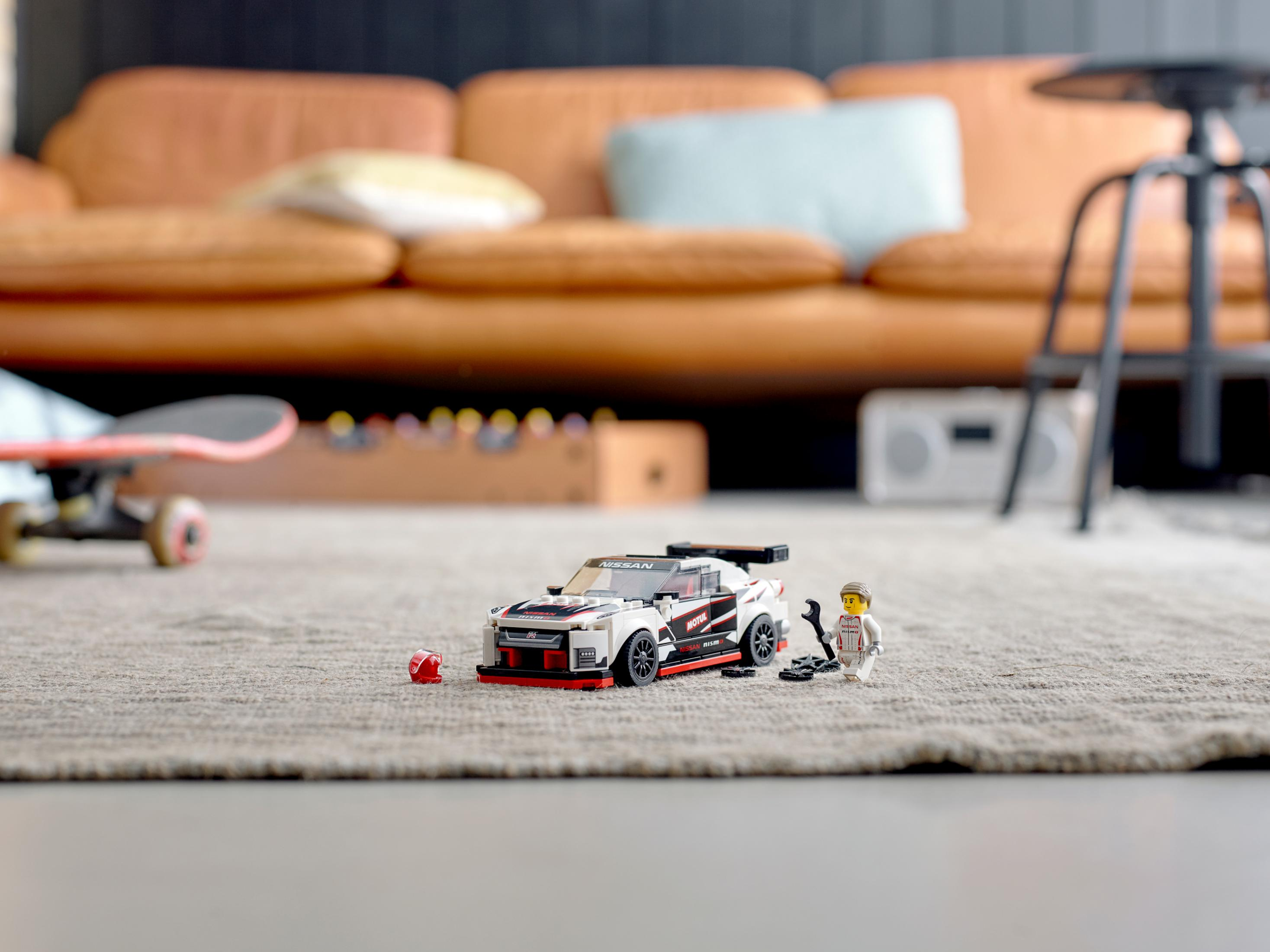 Modello Lego di un'auto da corsa bianca e nera con una minifigure e attrezzi su un tappeto.