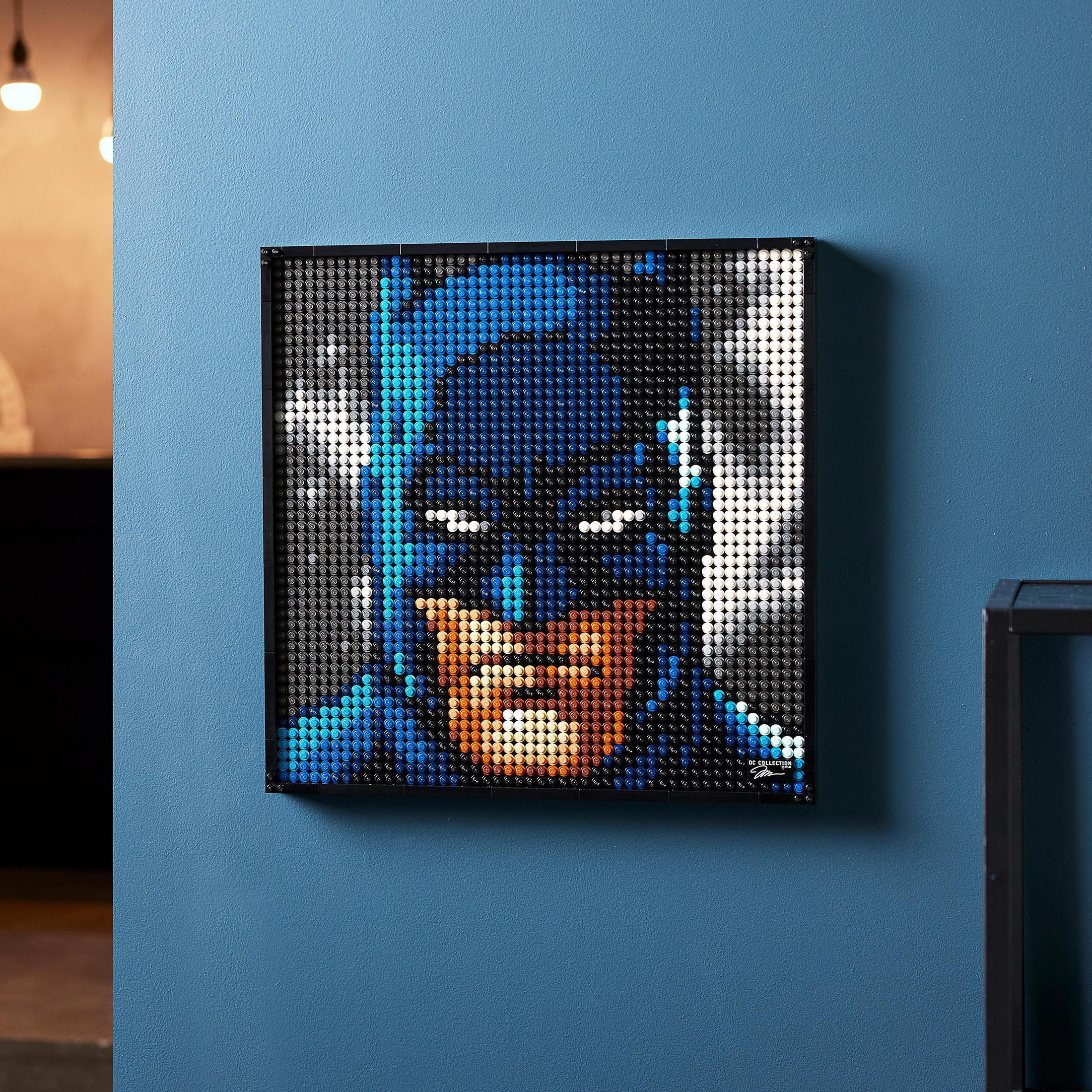 Mozaikowe dzieło sztuki Lego Batman wystawione na niebieskiej ścianie z czarną ramą.