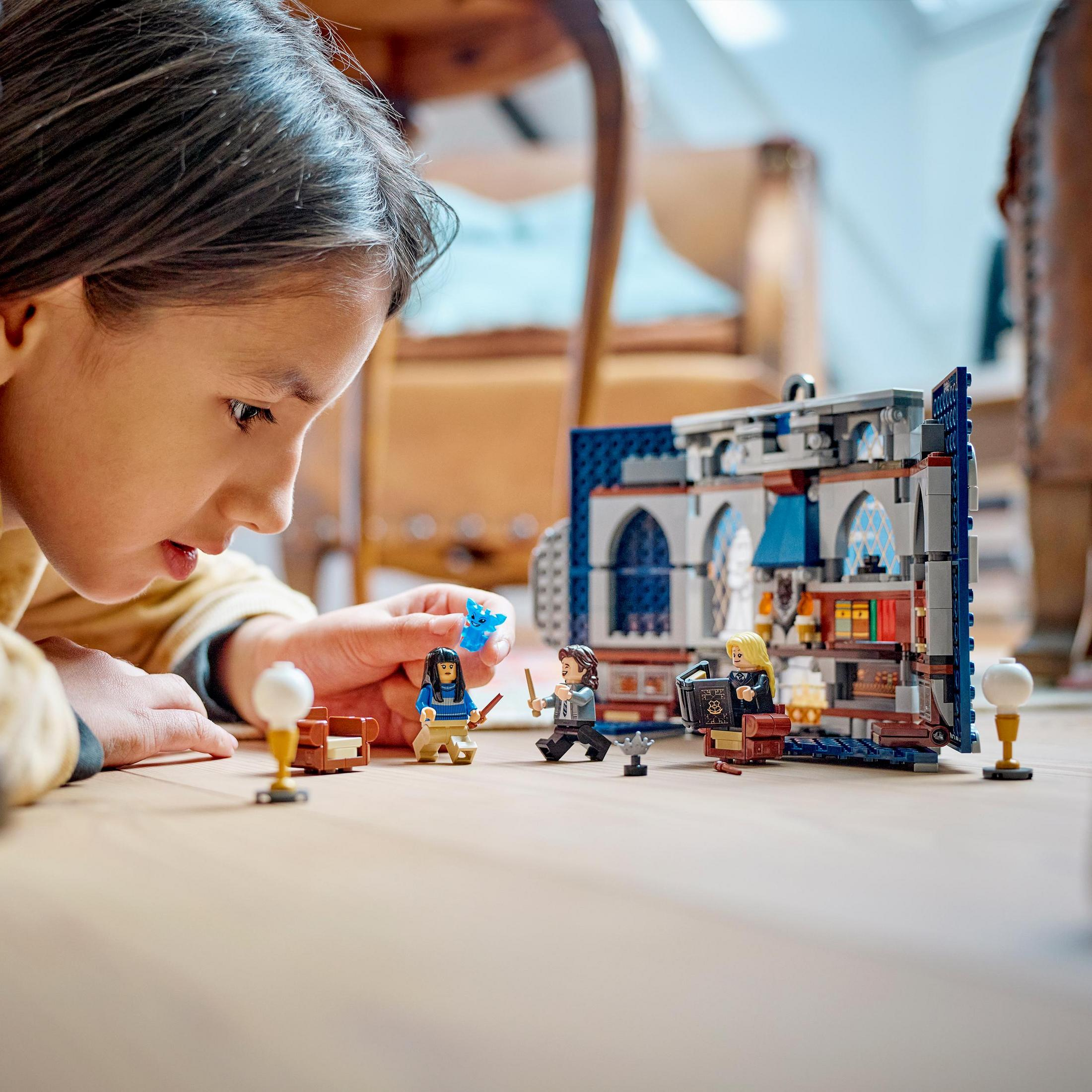 Ein Kind spielt mit einem Lego-Set mit Mini-Figuren und einem Gebäude.