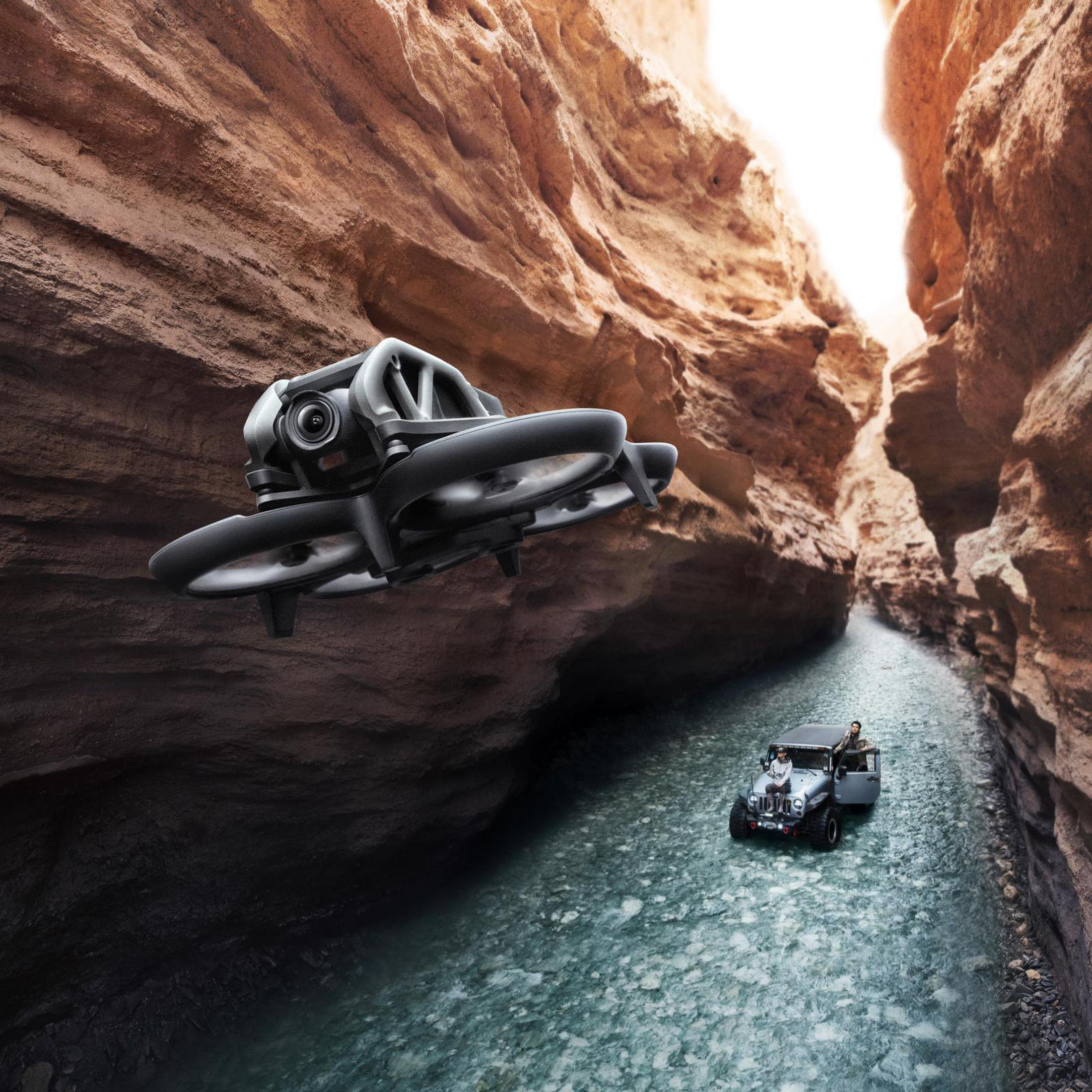 Un dron volando en un cañón con un jeep en el agua.