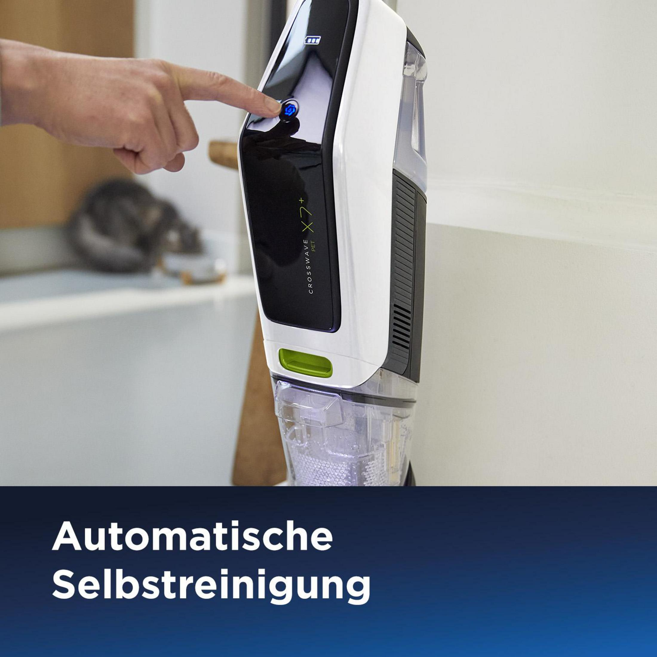 Eine Hand drückt einen Knopf auf einem weißen und schwarzen Staubsauger. Der Staubsauger steht aufrecht.