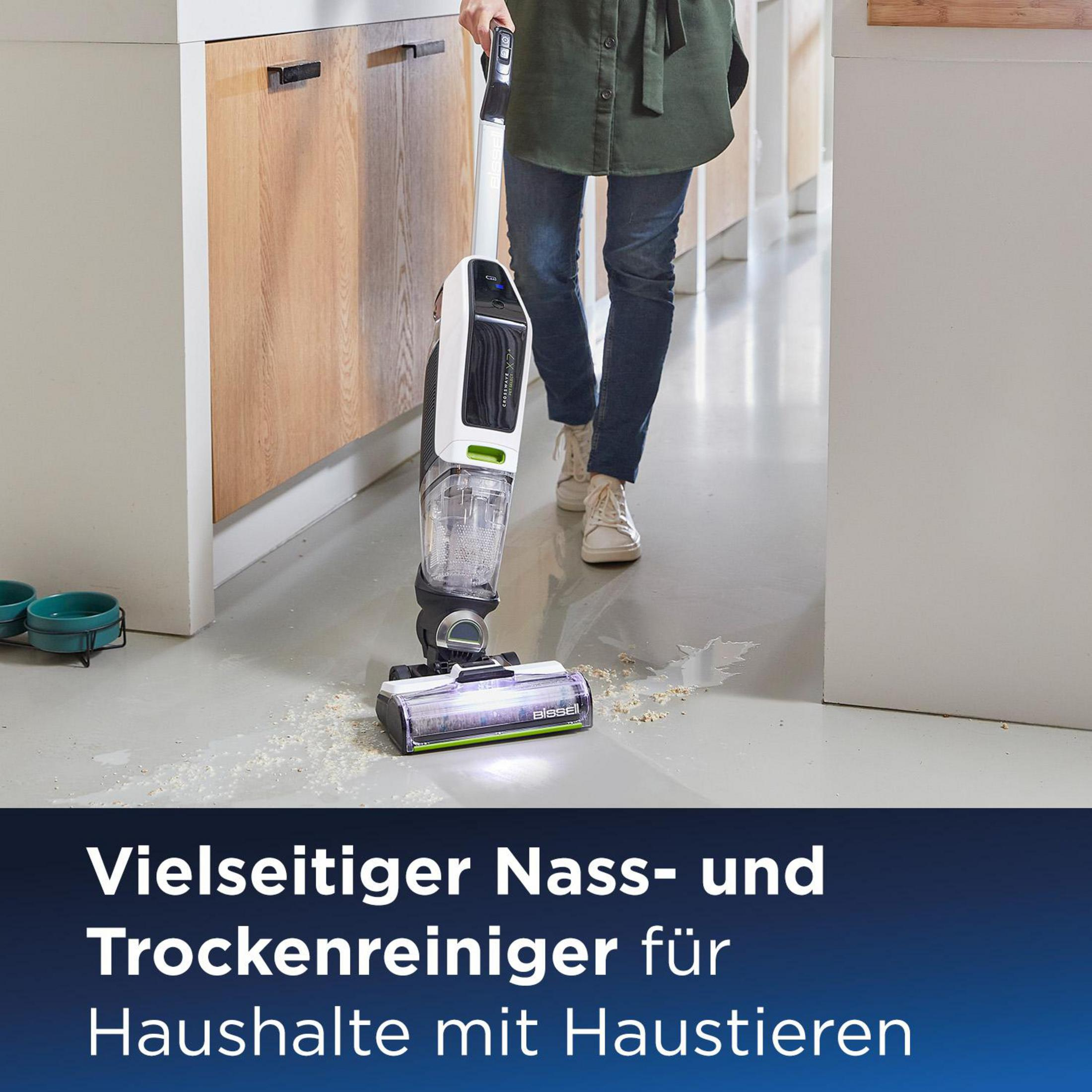 Eine Frau saugt mit einem kabellosen Staubsauger den Boden. Auf dem Boden liegt etwas Schmutz.
