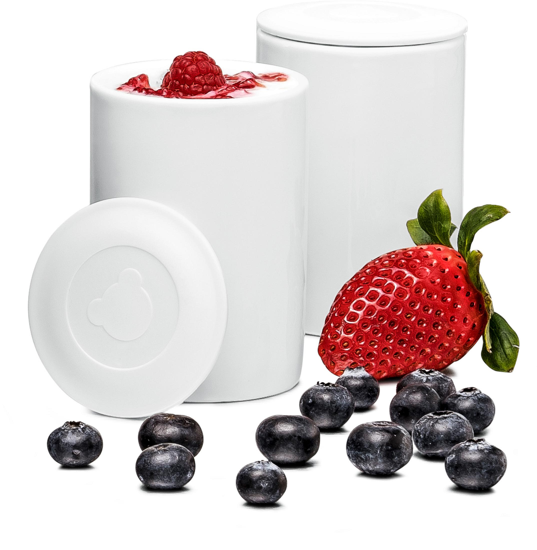 Weiße Behälter mit Obst, darunter eine Erdbeere und Blaubeeren.