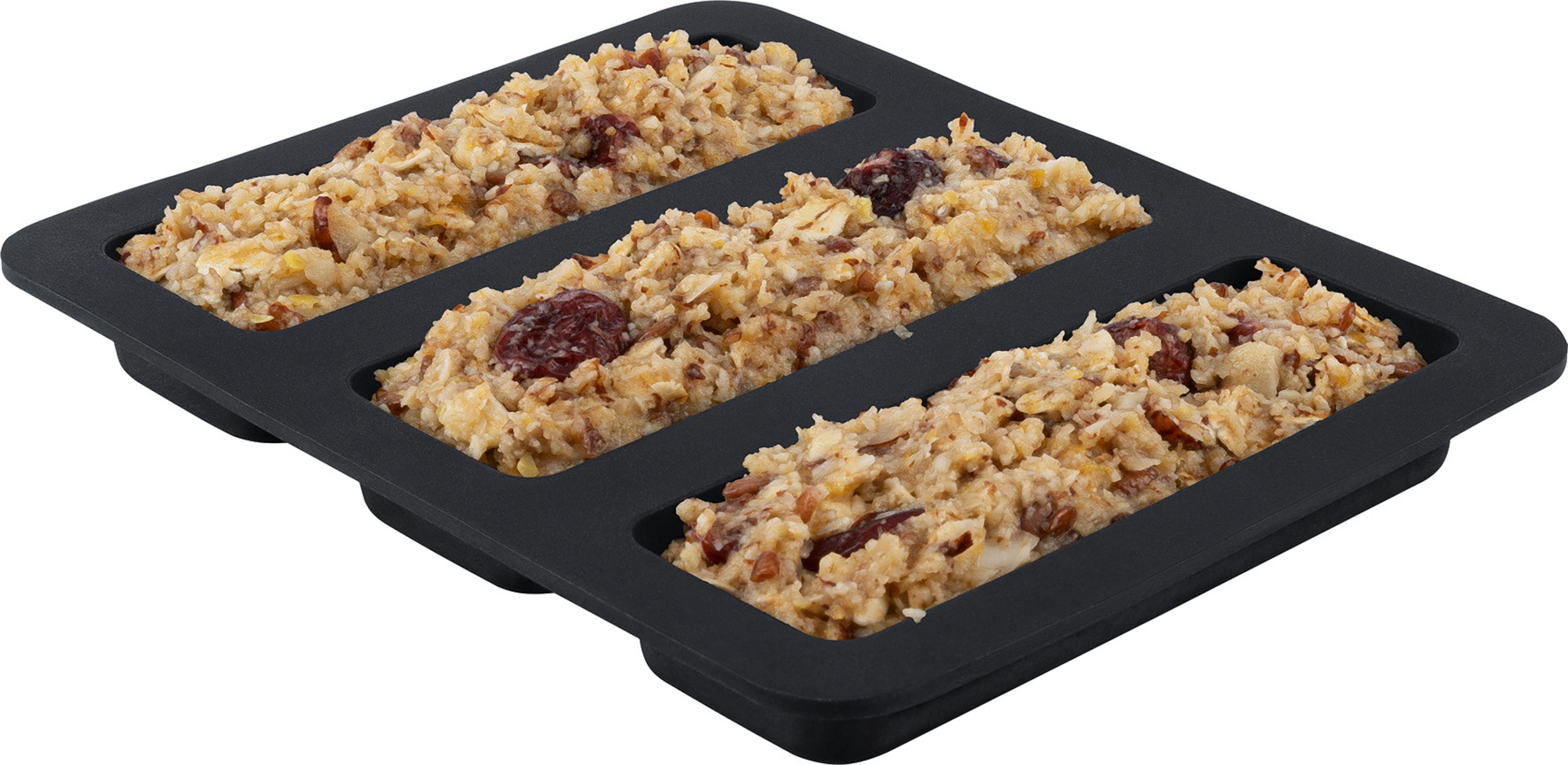 Drei Riegel gebackenes Granola in einem schwarzen rechteckigen Backblech. Zutaten sind Nüsse und Beeren.
