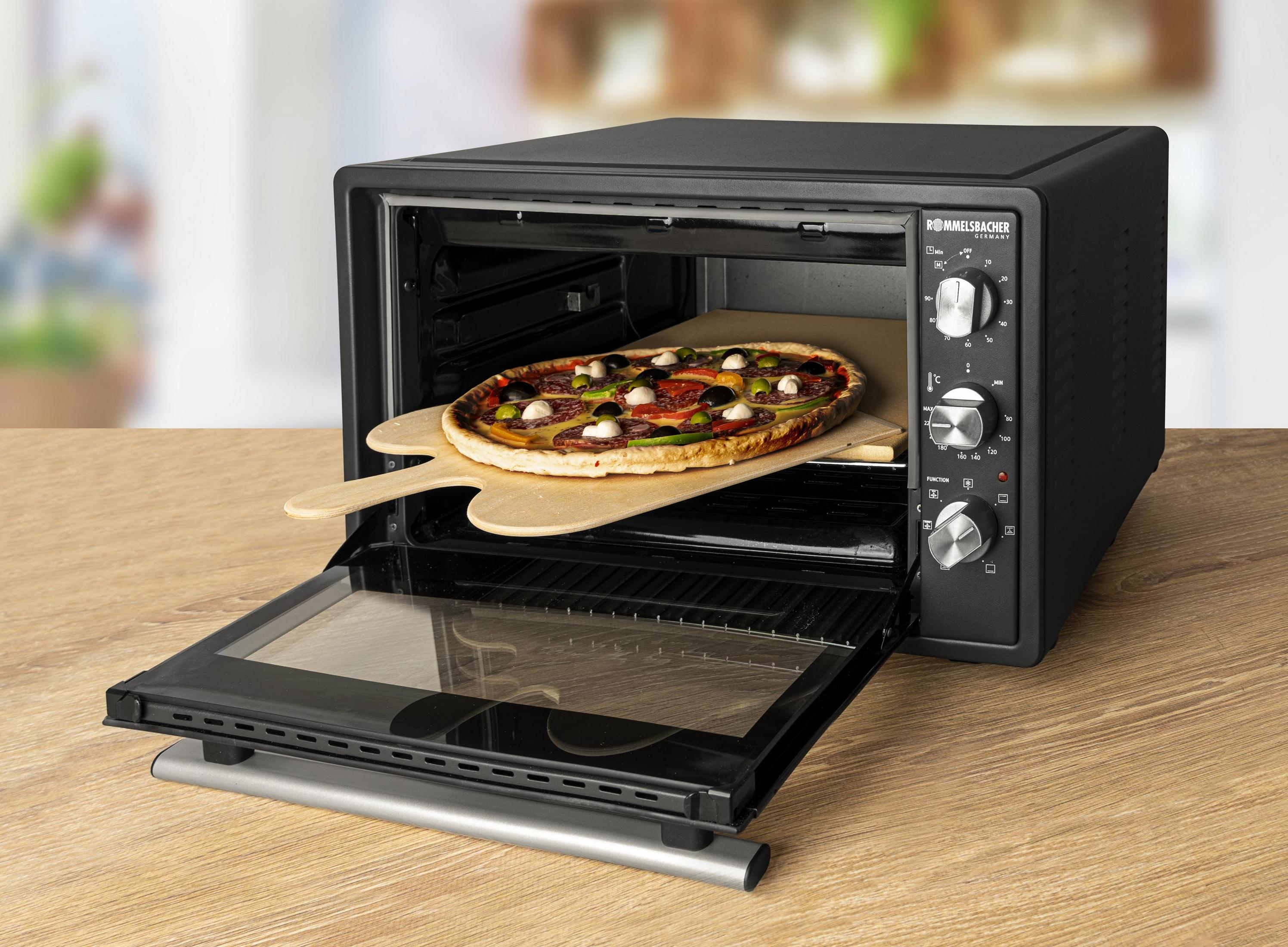 Eine Pizza auf einem Holzbrett in einem schwarzen Ofen.