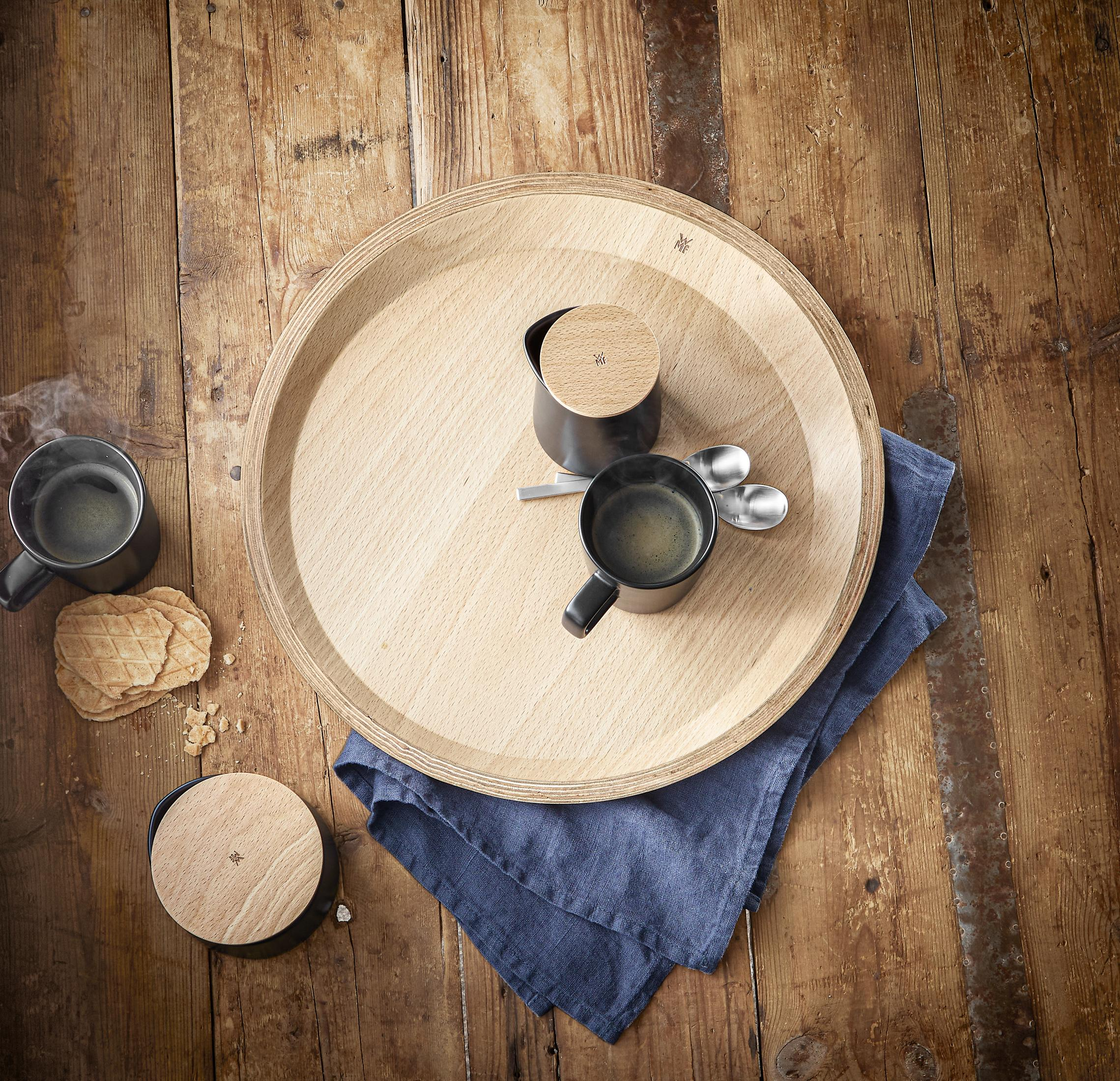 Ein Holztablett mit Kaffeetassen, Löffeln und einer blauen Serviette.