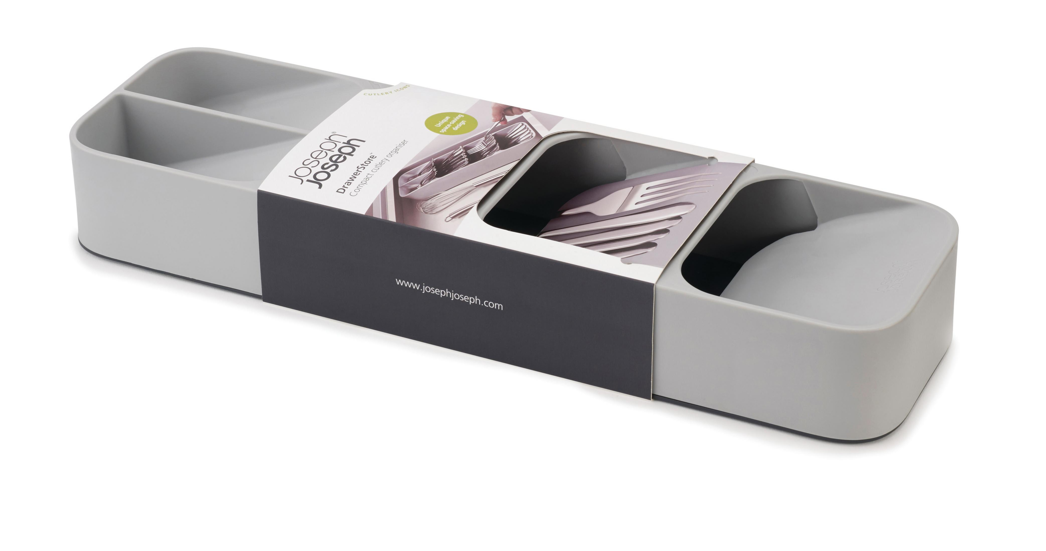 Organizador de cajones gris y blanco con compartimentos, embalaje visible. Fondo blanco.