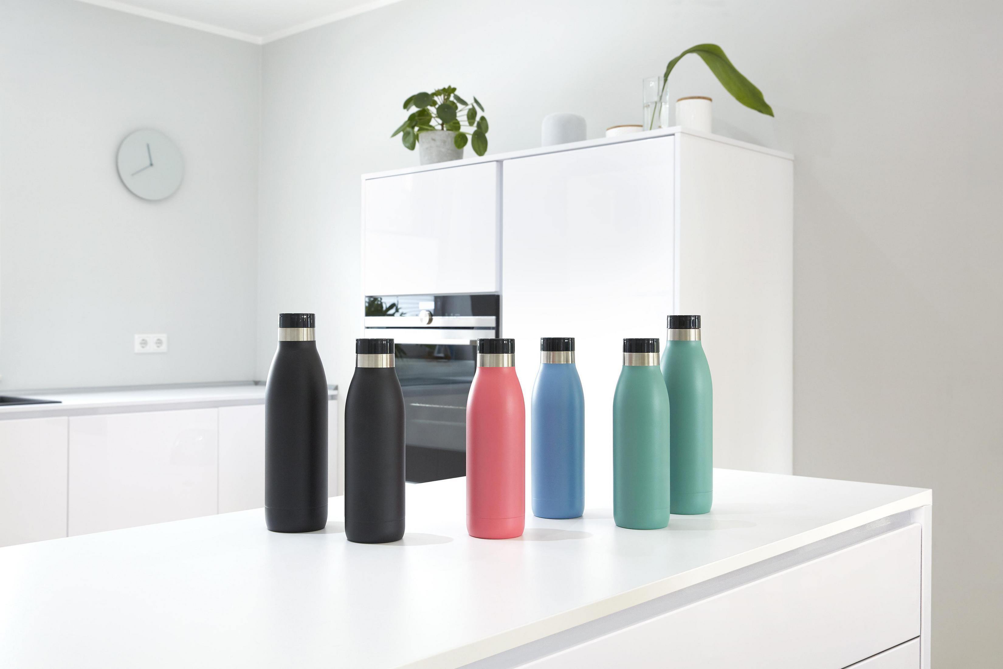 Eine Küchenzeile mit sechs bunten Wasserflaschen. Die Farben sind Schwarz, Rosa, Blau und Grün.