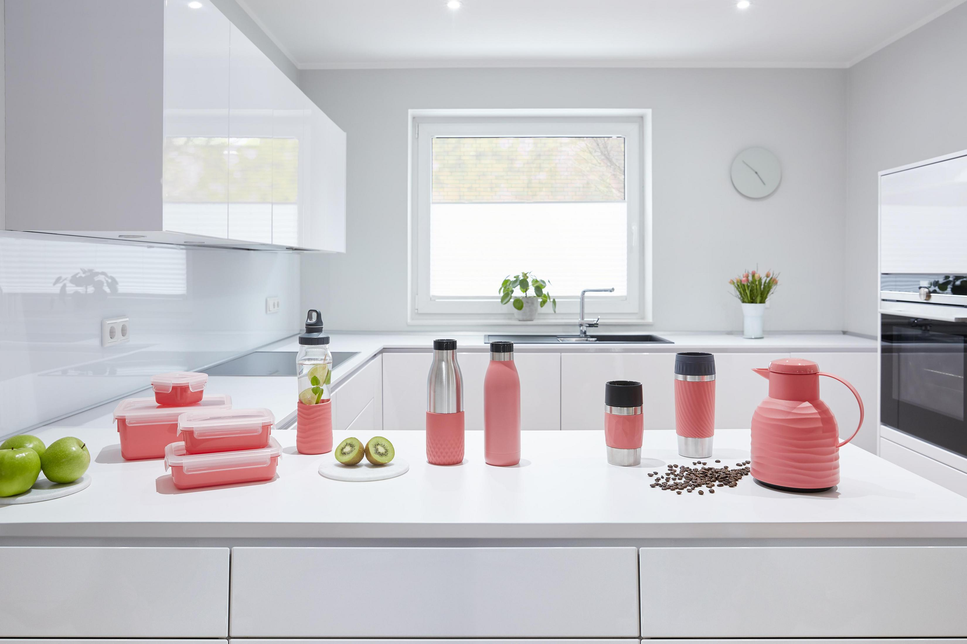 Küchentheke mit rosa Behältern, Thermoskanne, Tassen und Kaffeemaschine, mit Lebensmitteln.
