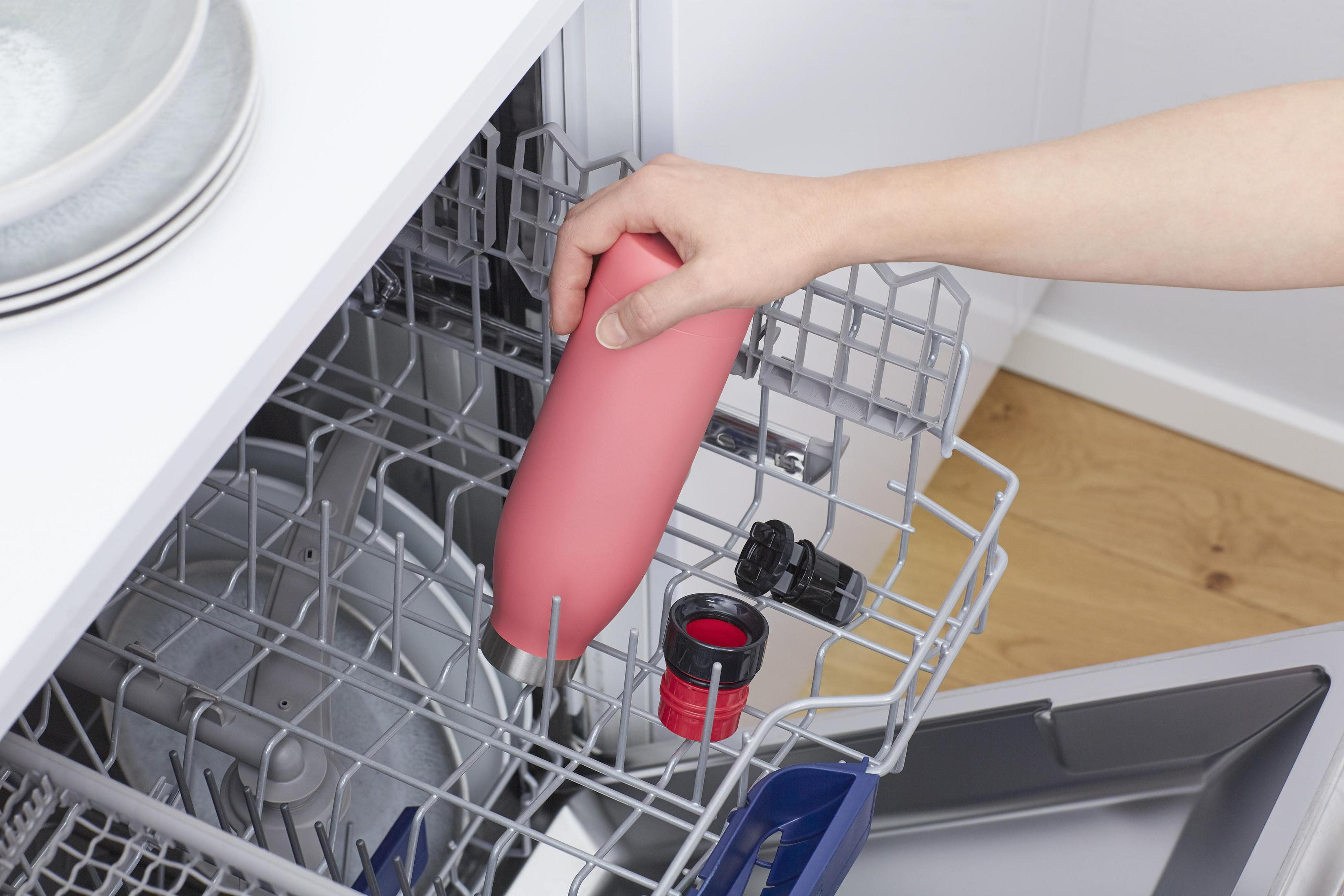Eine Person, die eine rosa Wasserflasche in ein Geschirrkorb legt.