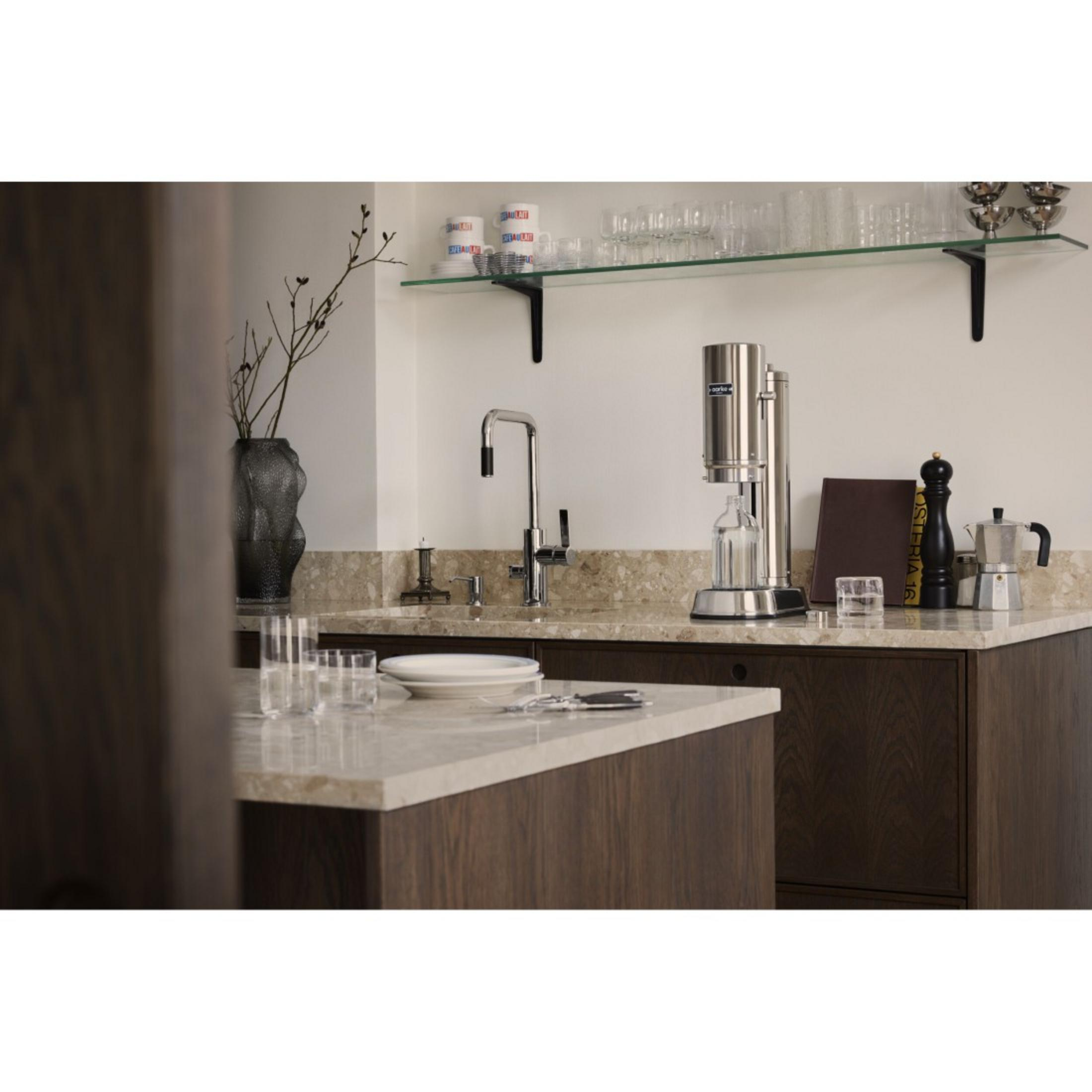 Kücheninterieur mit Spüle, Wasserhahn und Kaffeemaschine auf der Theke.