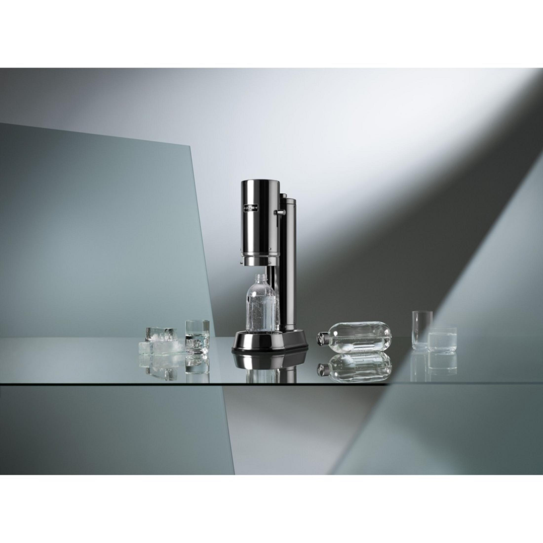 SodaStream-Maschine und Zubehör auf einer reflektierenden Oberfläche. Enthält Gläser und CO2-Tanks.