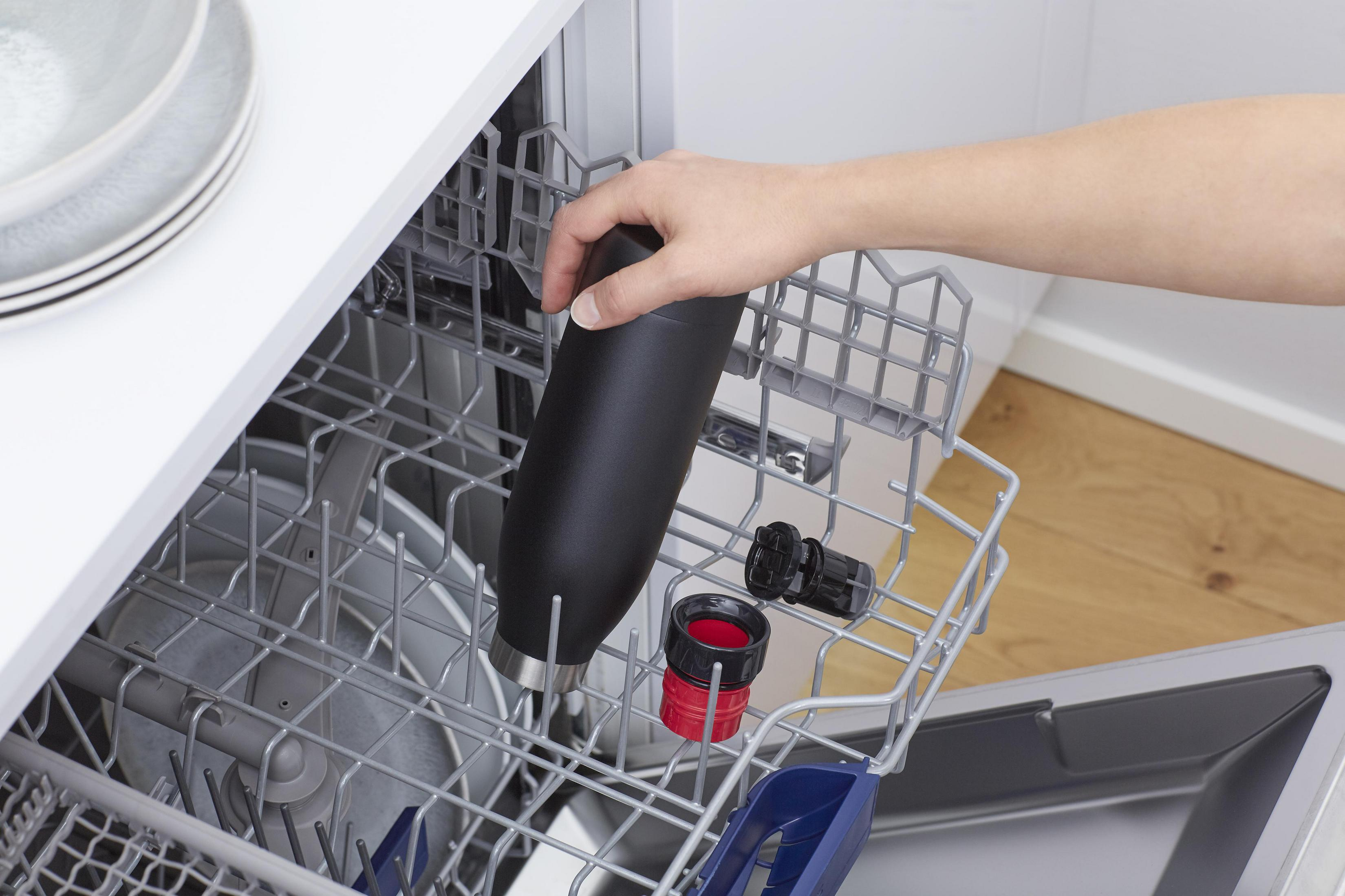 Eine schwarze Wasserflasche wird in eine Spülmaschine gestellt.