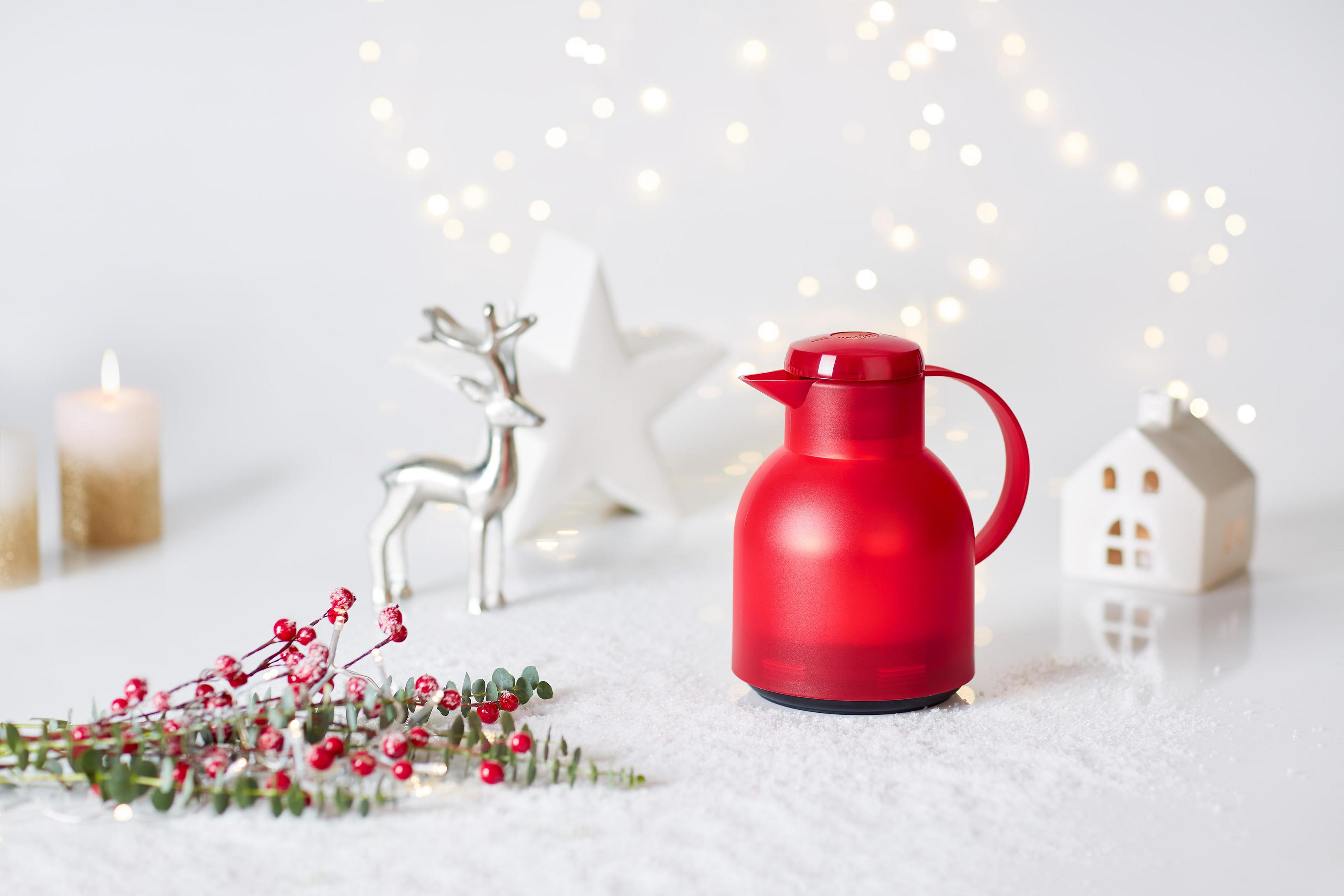 Eine rote Thermoskanne, ein silbernes Rentier und ein weißer Stern mit Lichtern und Schnee.