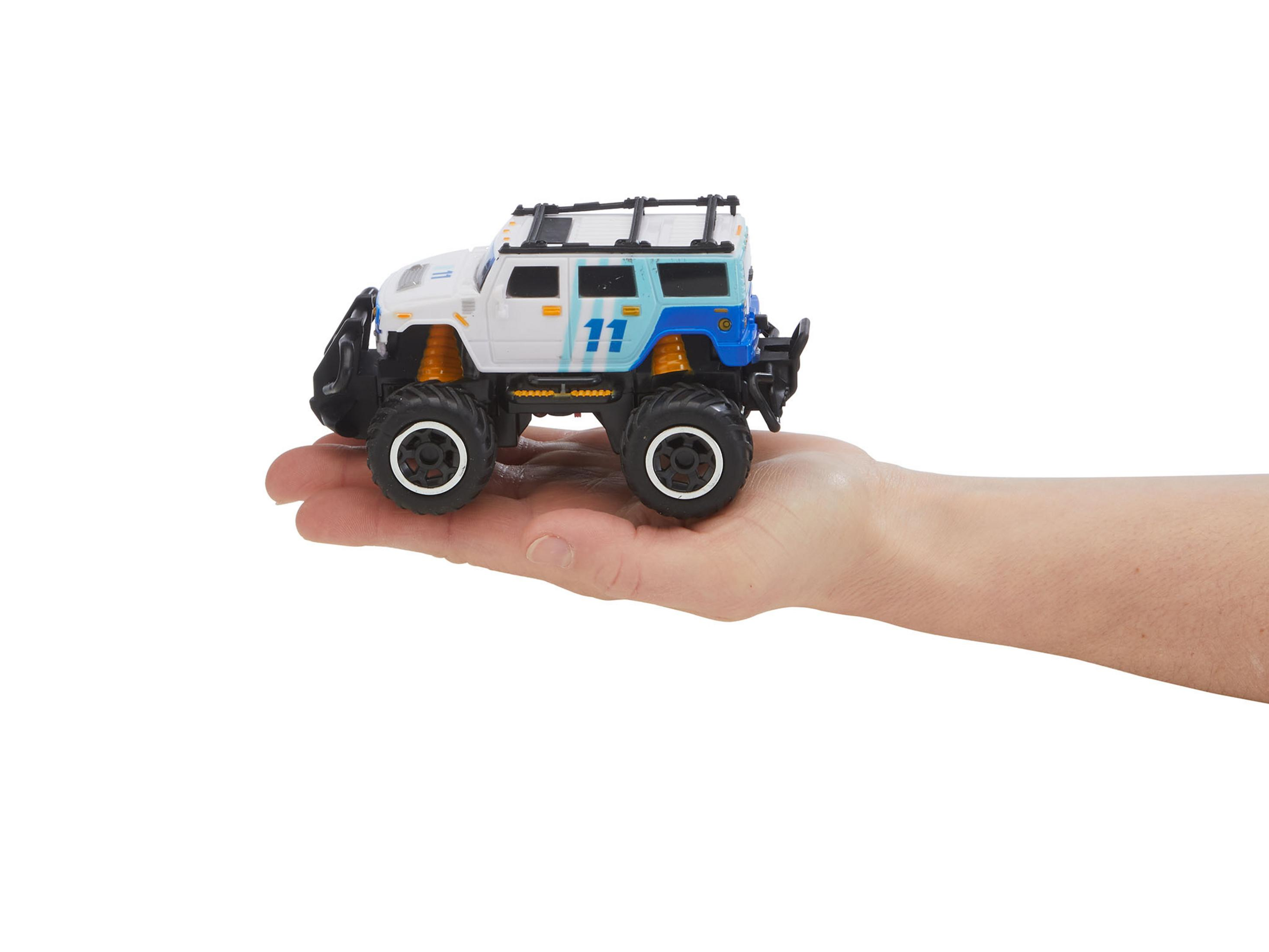 Die Hand eines Kindes hält einen Spielzeug-SUV auf weißem Hintergrund.