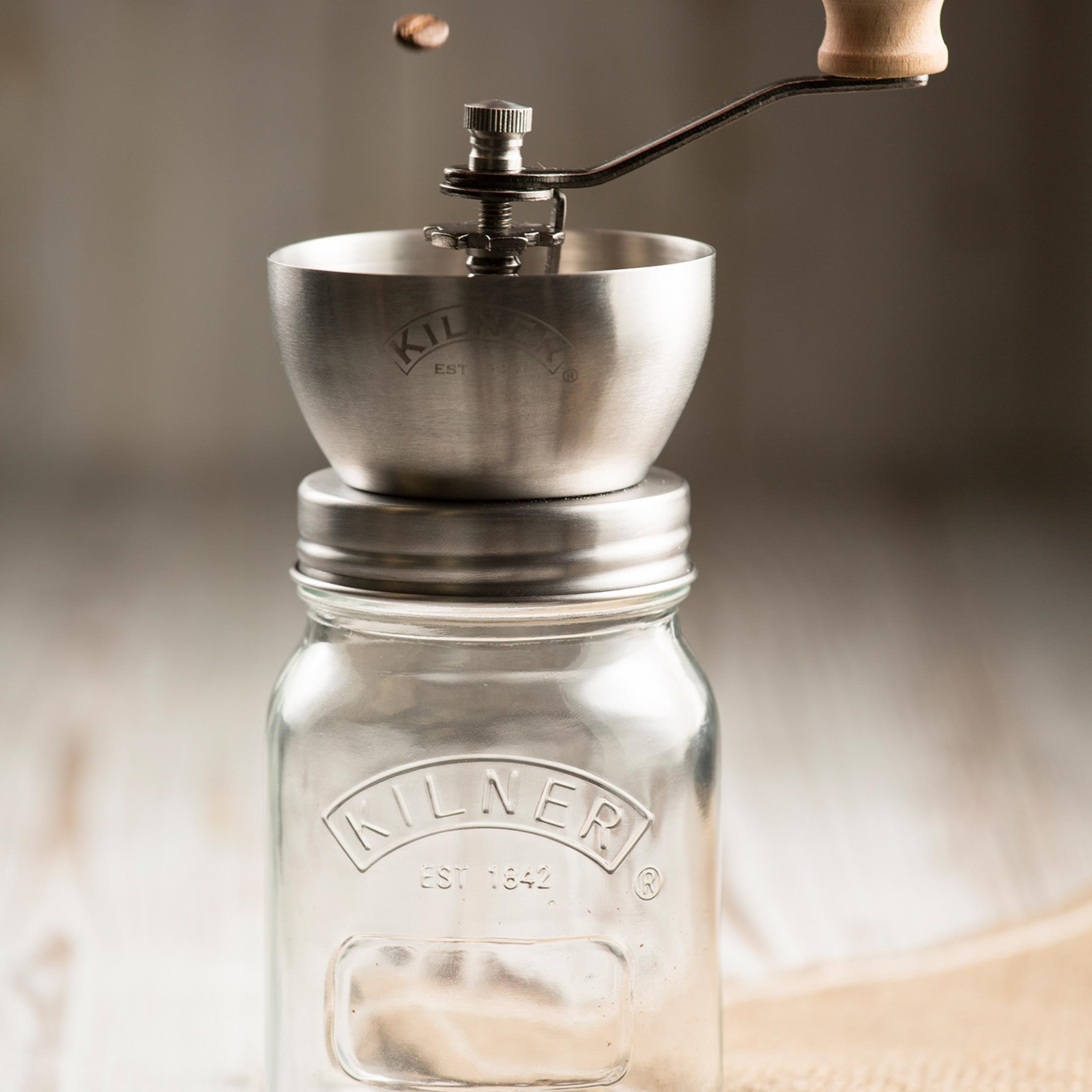Eine Kaffeemühle mit Griff auf einem Glas mit 'KILNER'-Logo.