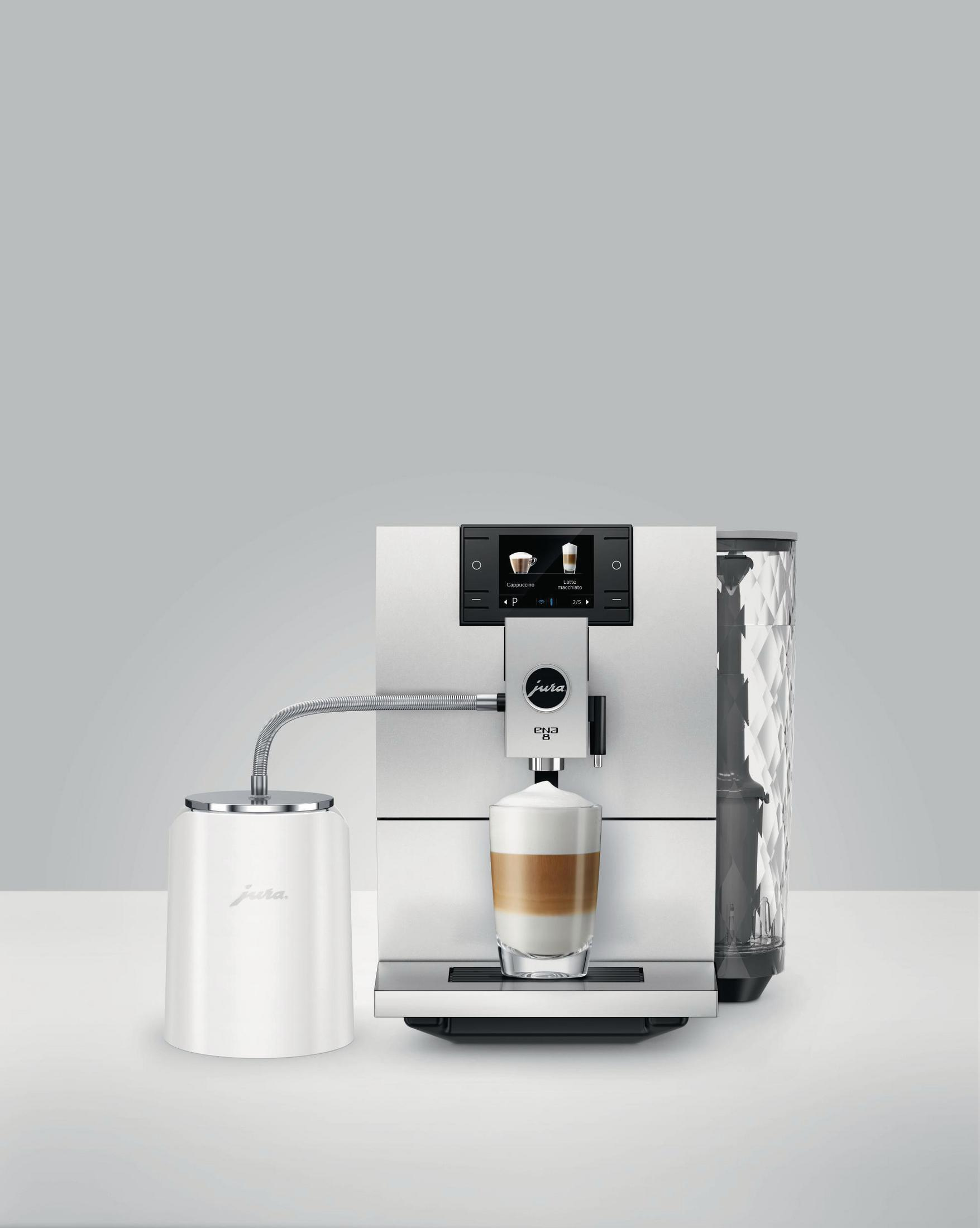 Weiße Jura Kaffeemaschine. Ein Latte wird zubereitet. Weißer Milchbehälter. Grauer Hintergrund.