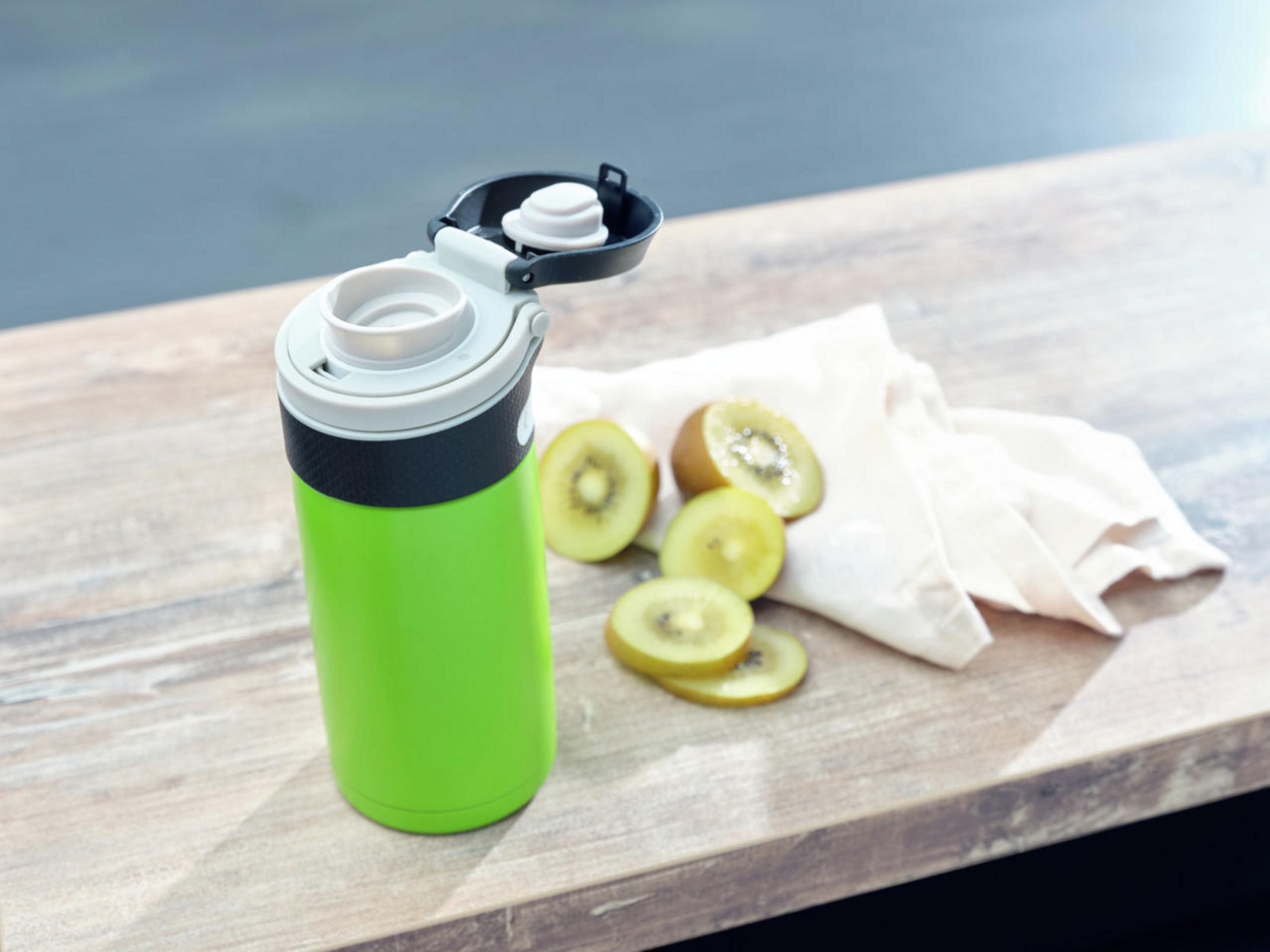 Eine grüne Wasserflasche neben Kiwischeiben auf einer Holzoberfläche.