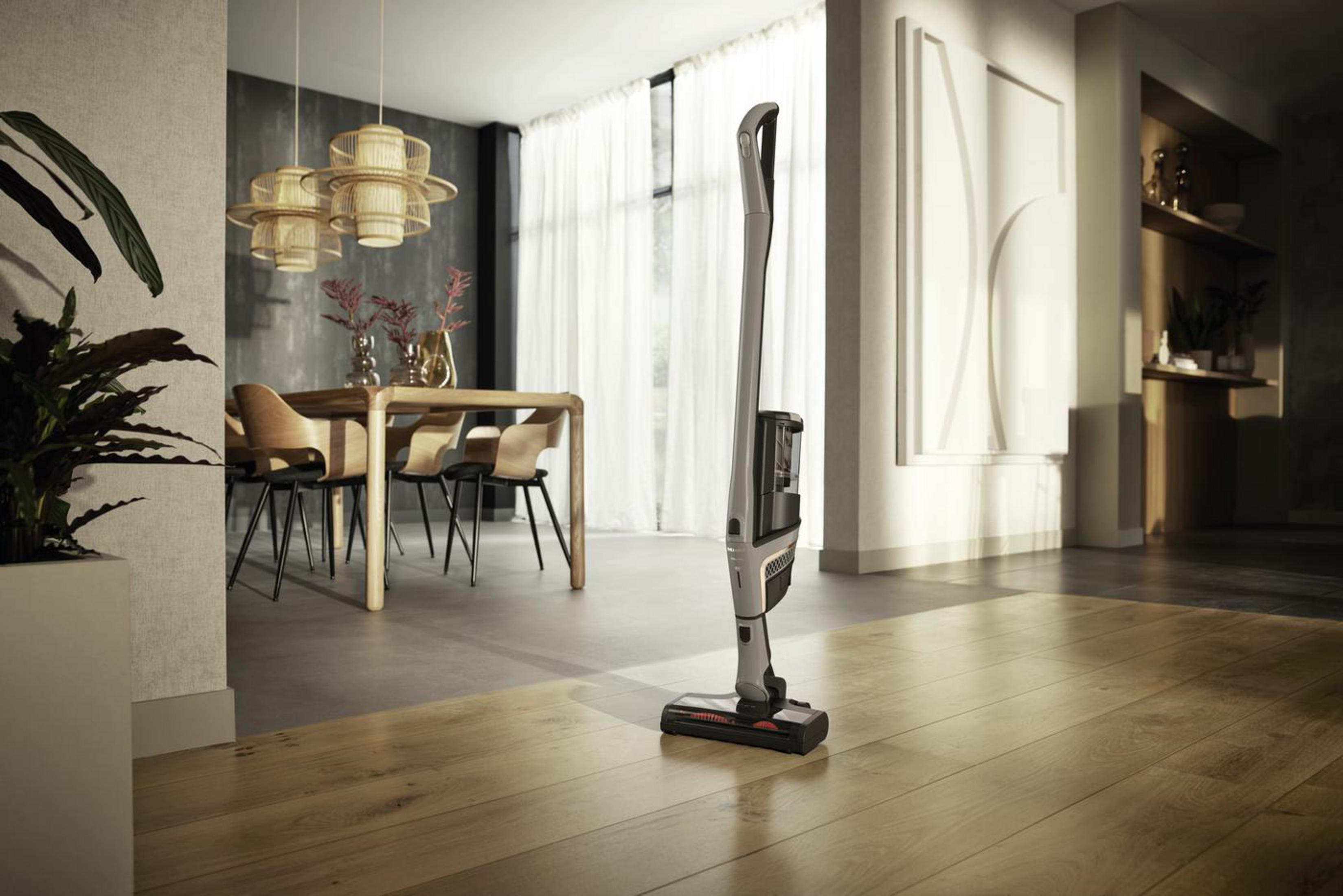Un salon moderne avec un aspirateur debout. Meubles: table, chaises et tapis.