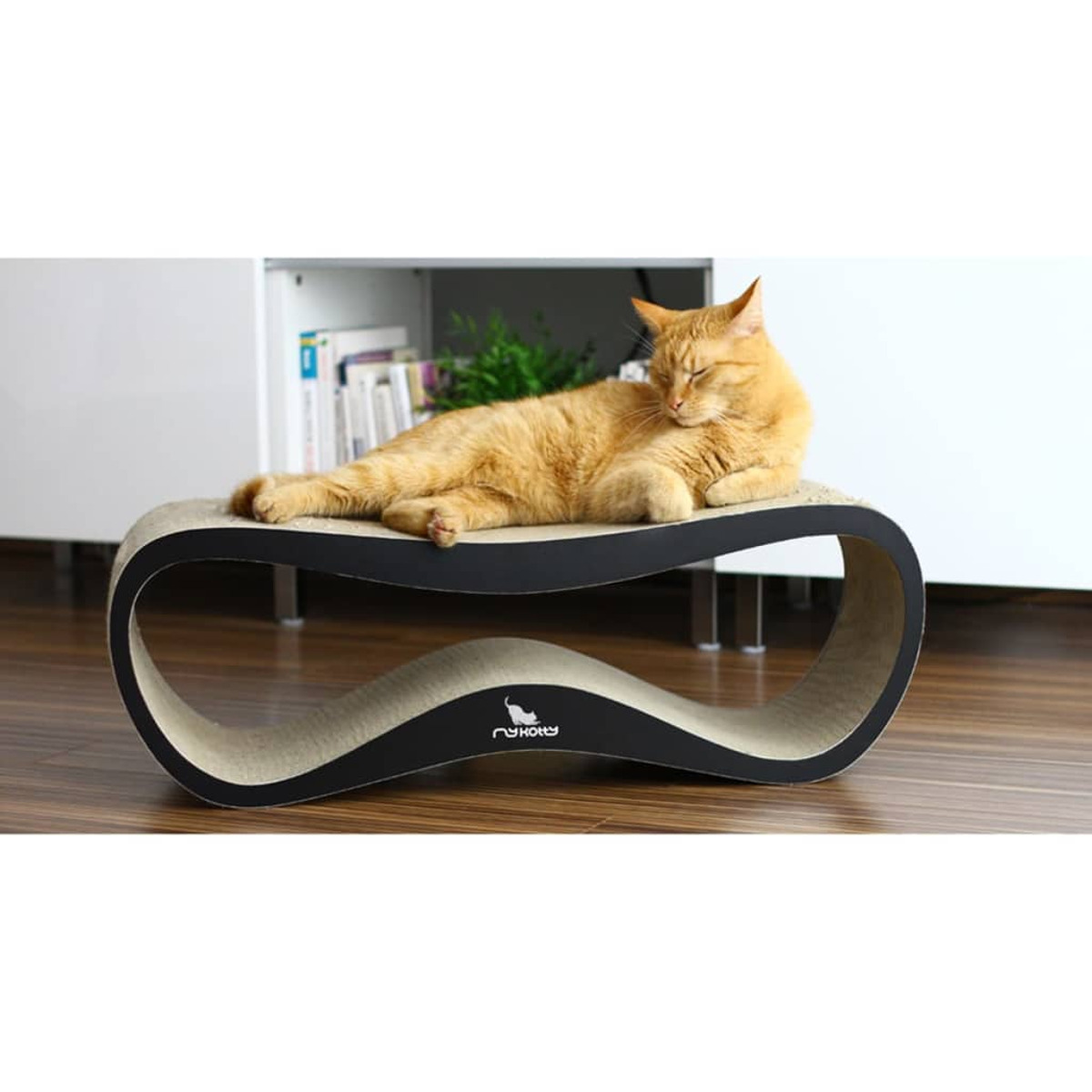 Gatto arancione che si rilassa su un tiragraffi. Il tiragraffi è curvo e fatto di cartone.