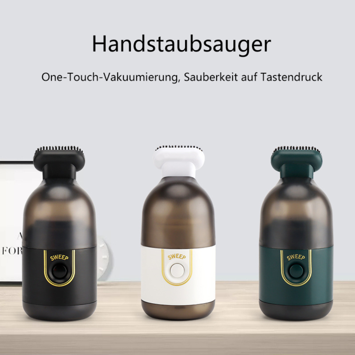 Drei Handstaubsauger. Schwarz, braun und grün, mit einem Knopf, stehen auf einer hellen Oberfläche.