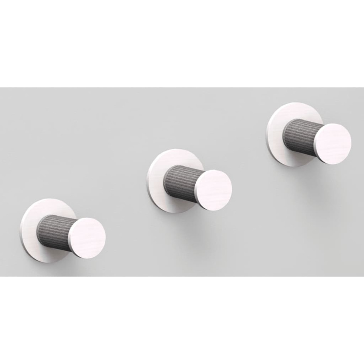 Tres perchas plateadas montadas en una pared gris claro. Los ganchos son cilíndricos.