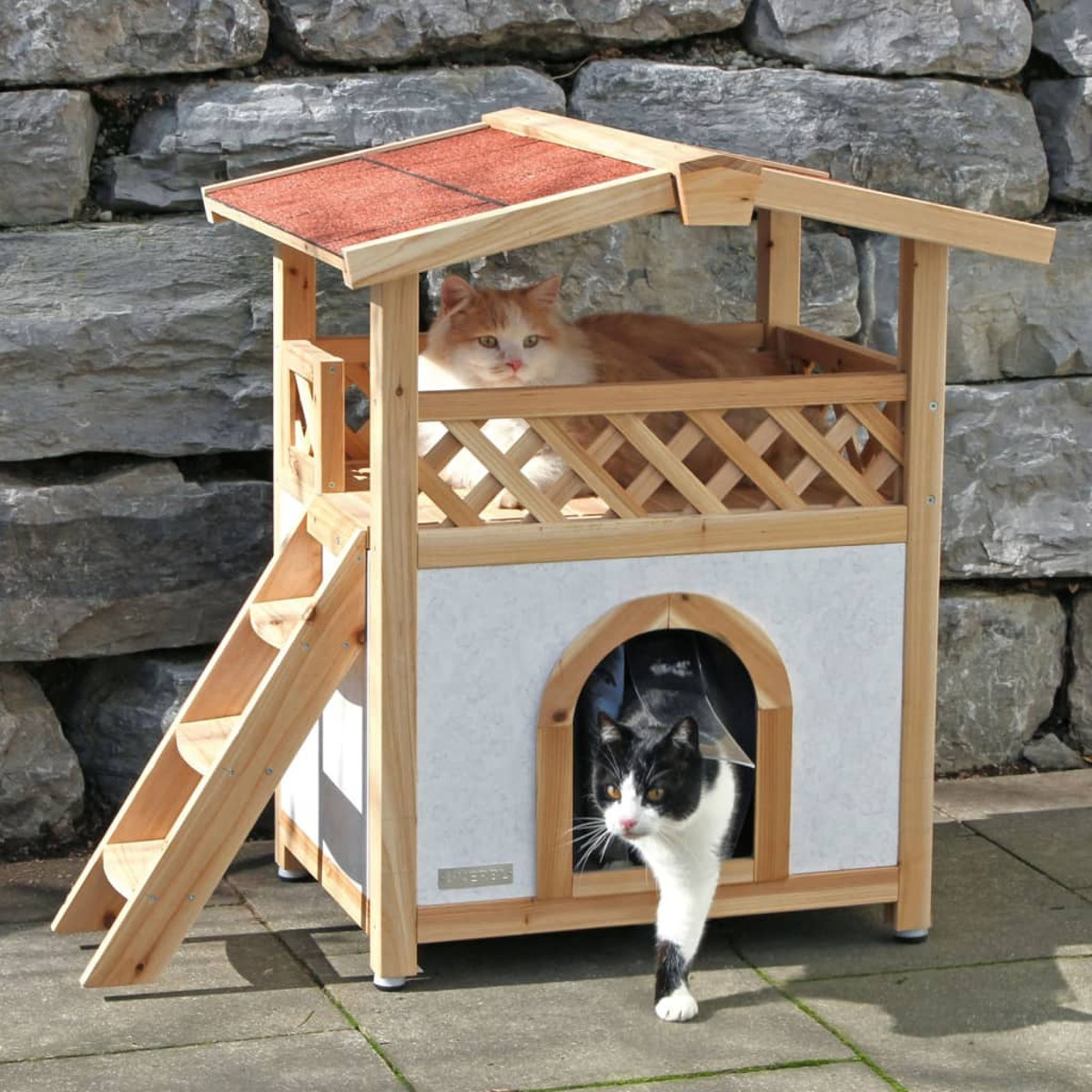 Katzenhaus aus Holz mit zwei Katzen. Eine Katze ist auf dem Dach, eine am Eingang.