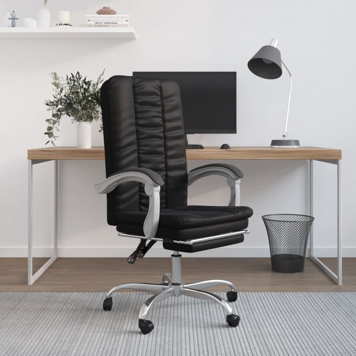 Schwarzer Leder-Bürostuhl, in einem Raum mit Schreibtisch, Lampe und Pflanze.