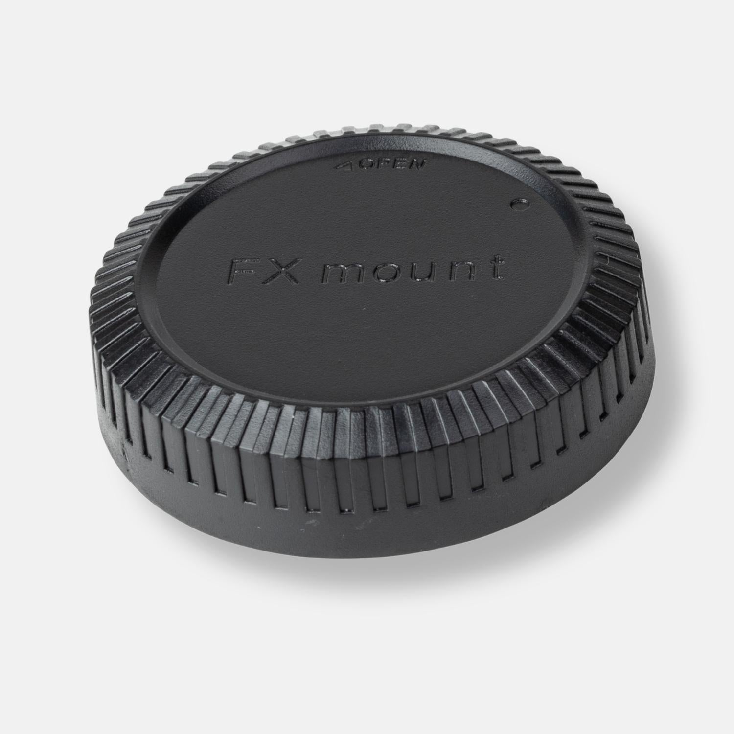 Schwarzer Objektivdeckel mit 'FX mount'-Text und geriffeltem Griff, vor hellgrauem Hintergrund.