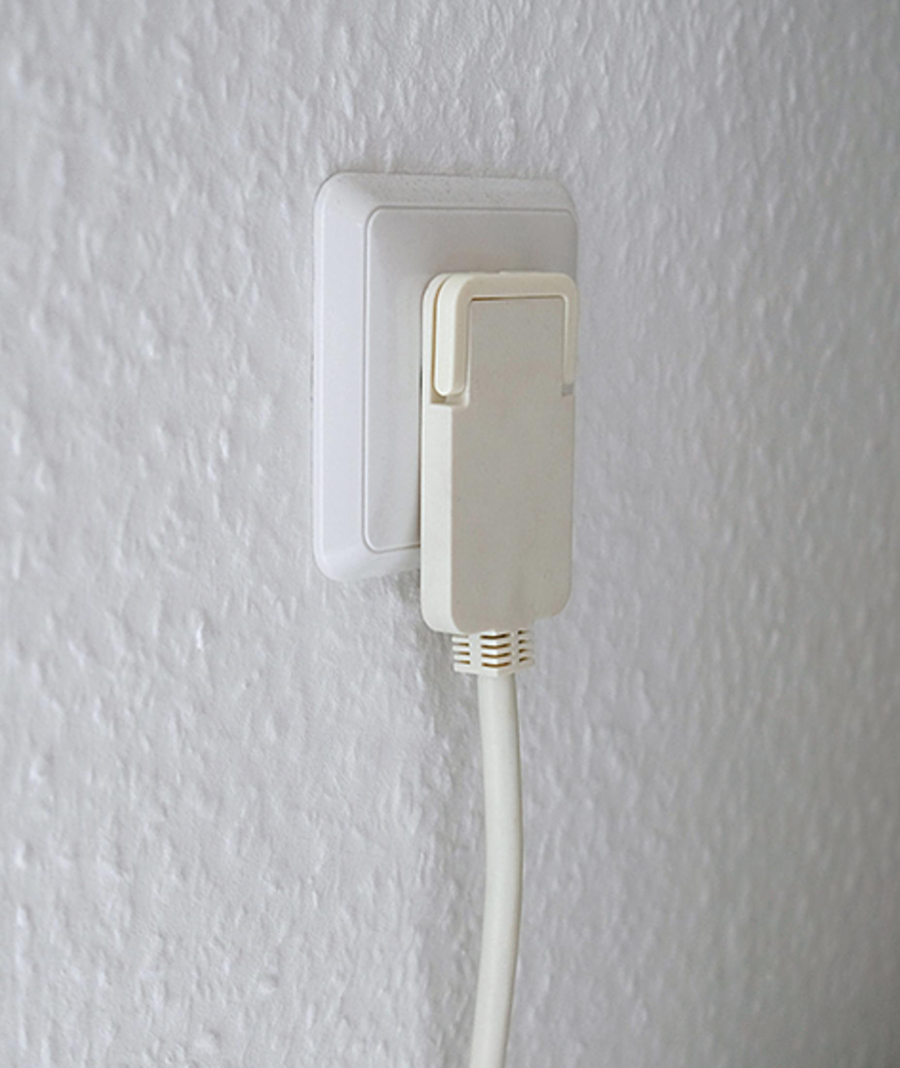 Weiße Steckdose mit angeschlossenem Stecker und Kabel.