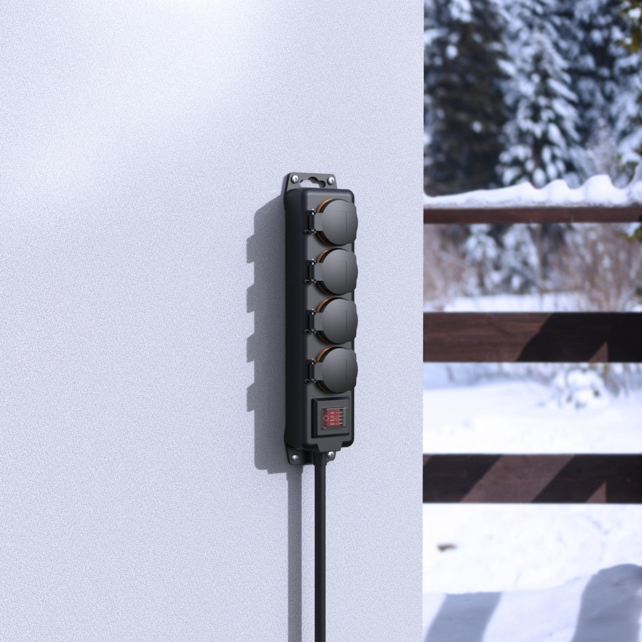 Czarna listwa zasilająca zamontowana na białej ścianie, z czterema gniazdami i czerwonym przełącznikiem.