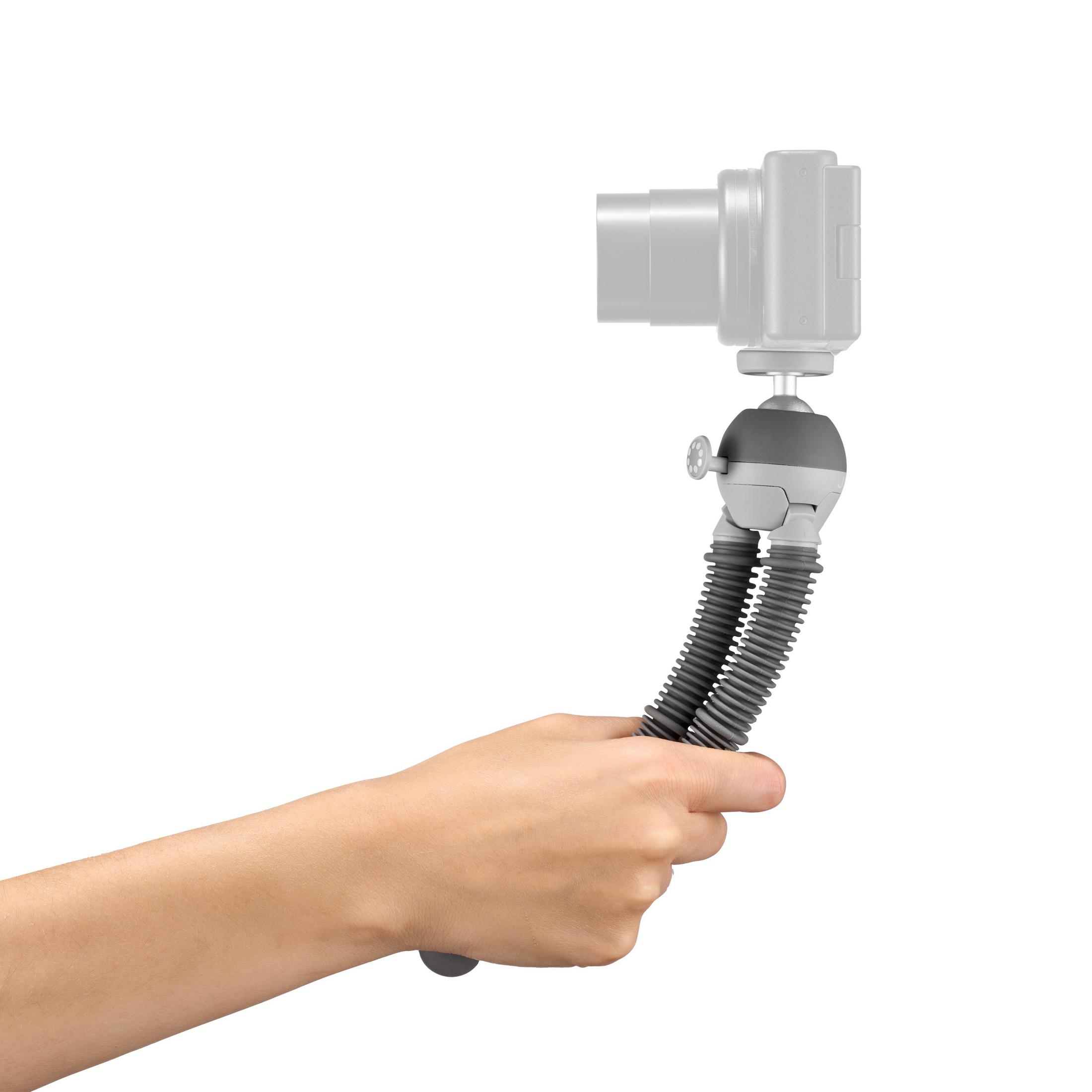 Une personne tenant un trépied flexible avec un appareil photo attaché. Le trépied est gris et noir, sur fond blanc.