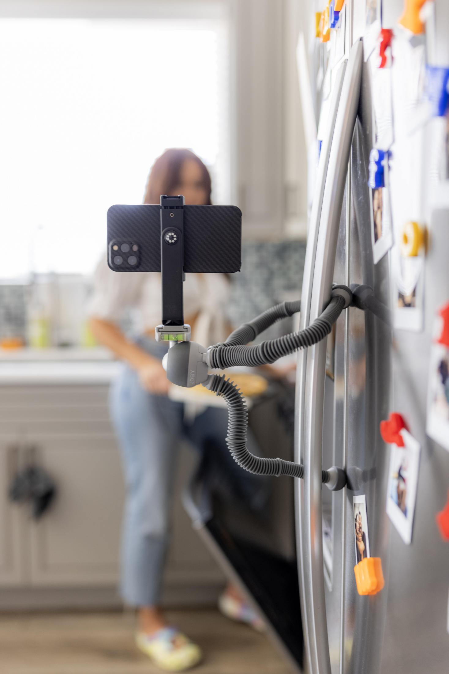 Smartfon zamontowany na elastycznym statywie przymocowanym do lodówki, nagrywający.
