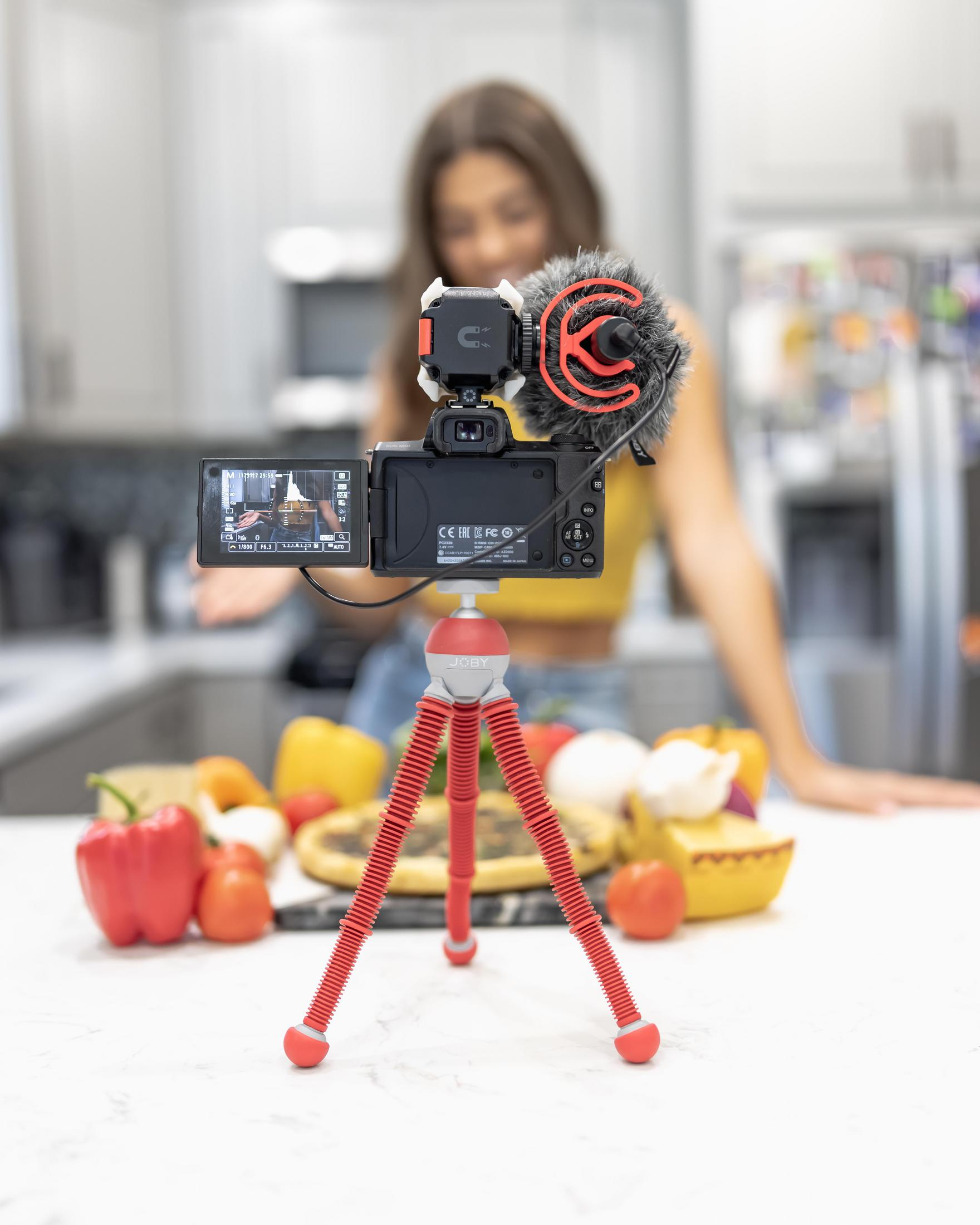 Vlogger mit Kamera auf Stativ, filmt in der Küche. Zutaten davor.