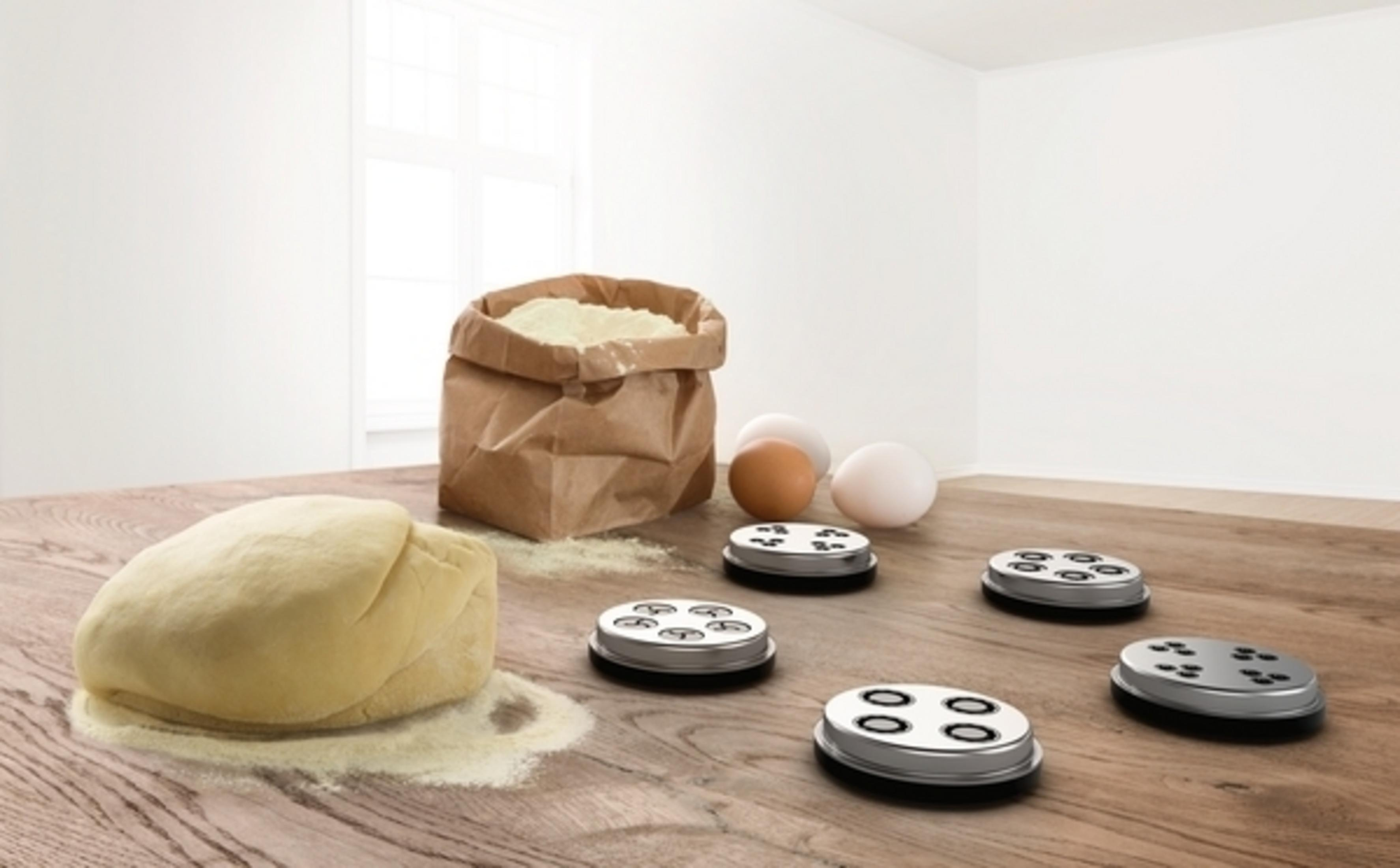 Ingredientes para pasta. Harina, huevos, accesorios de máquina de pasta y una bola de masa en madera.