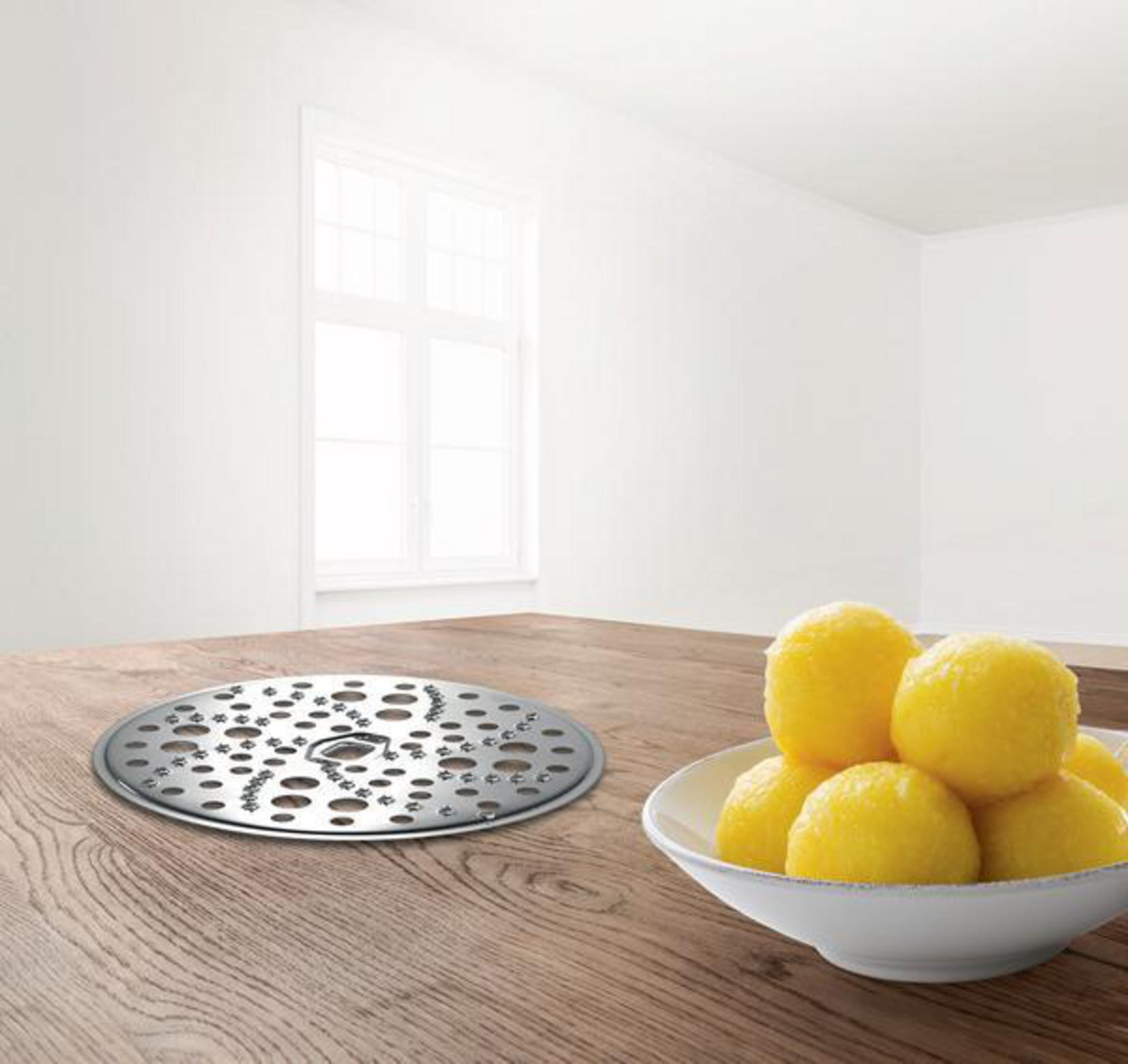 Stół z metalowym dyskiem i miską żółtych knedli. Biały pokój, okno w tle.