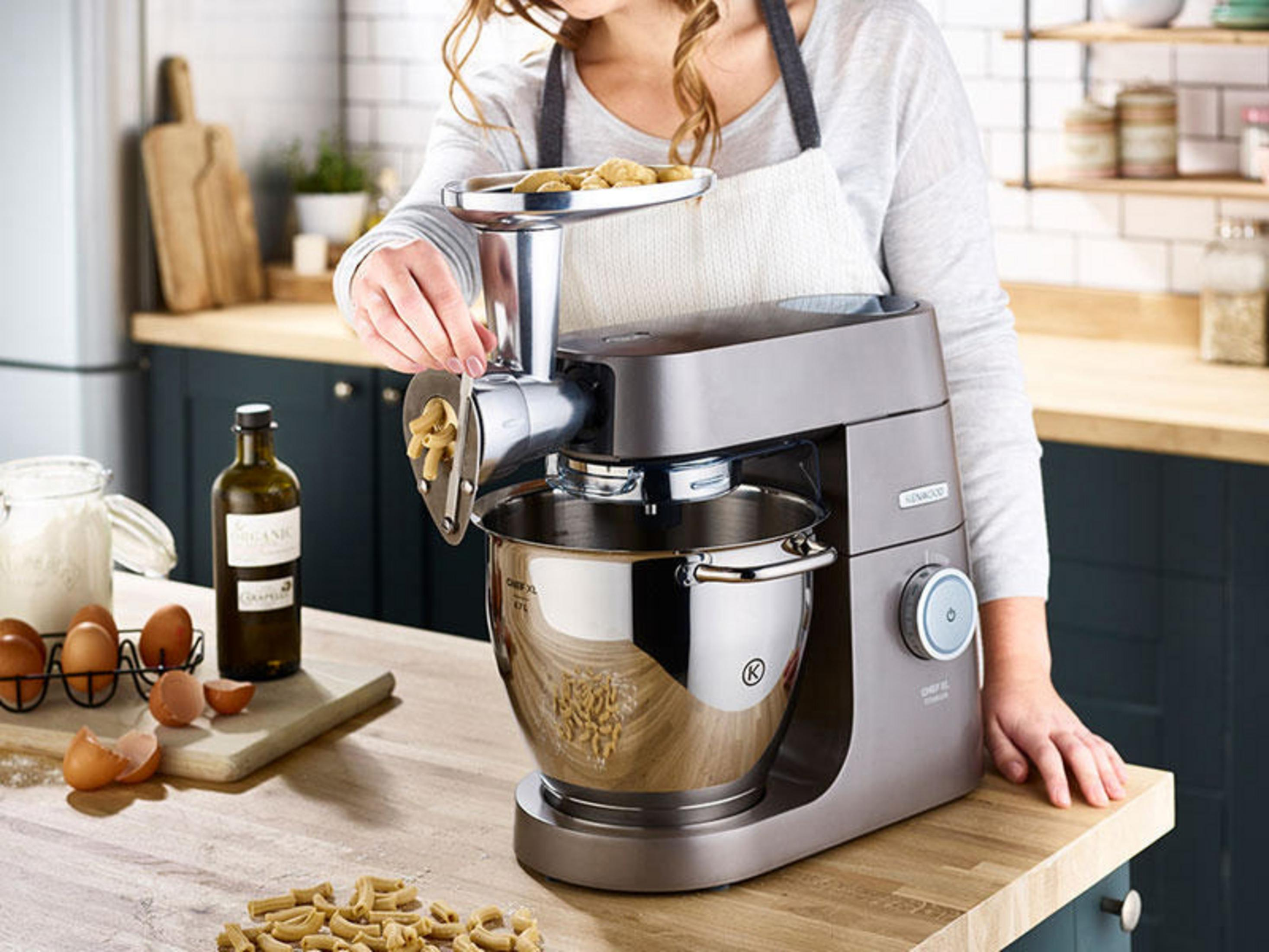 Kobieta używająca robota kuchennego Kenwood. Składniki i miska na blacie. Kuchnia w tle.