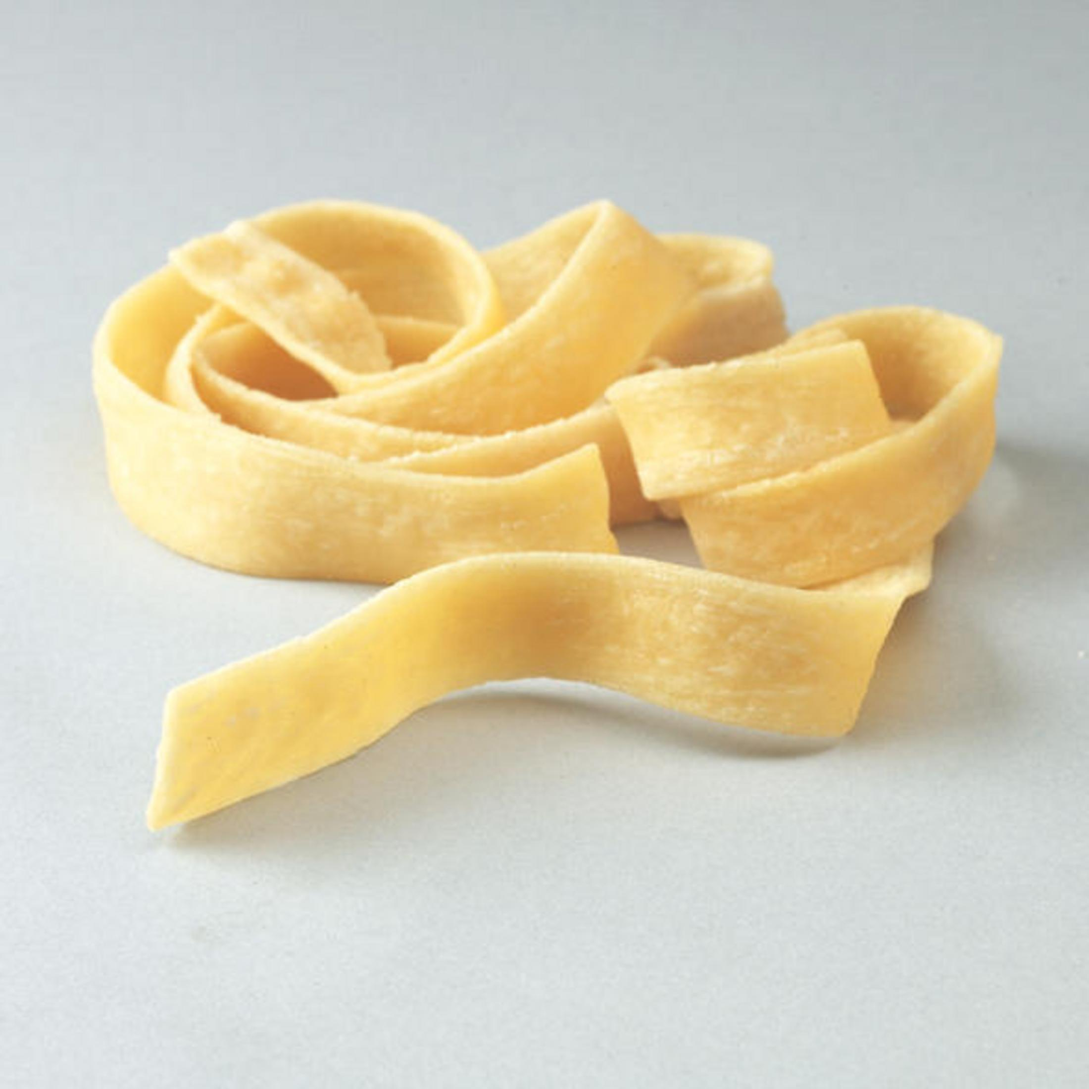 Gelbe Fettuccine-Nudelbänder auf hellgrauer Oberfläche.