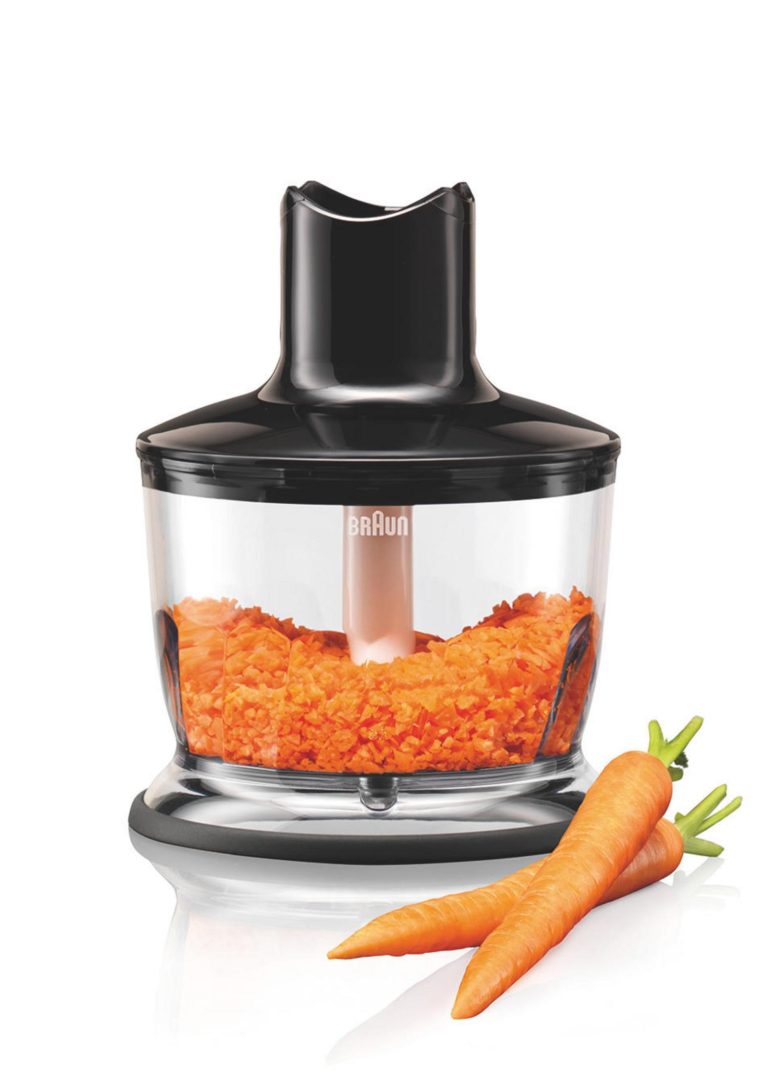 Ein schwarzer und klarer Food Processor mit gehackten Karotten und zwei Karotten daneben.
